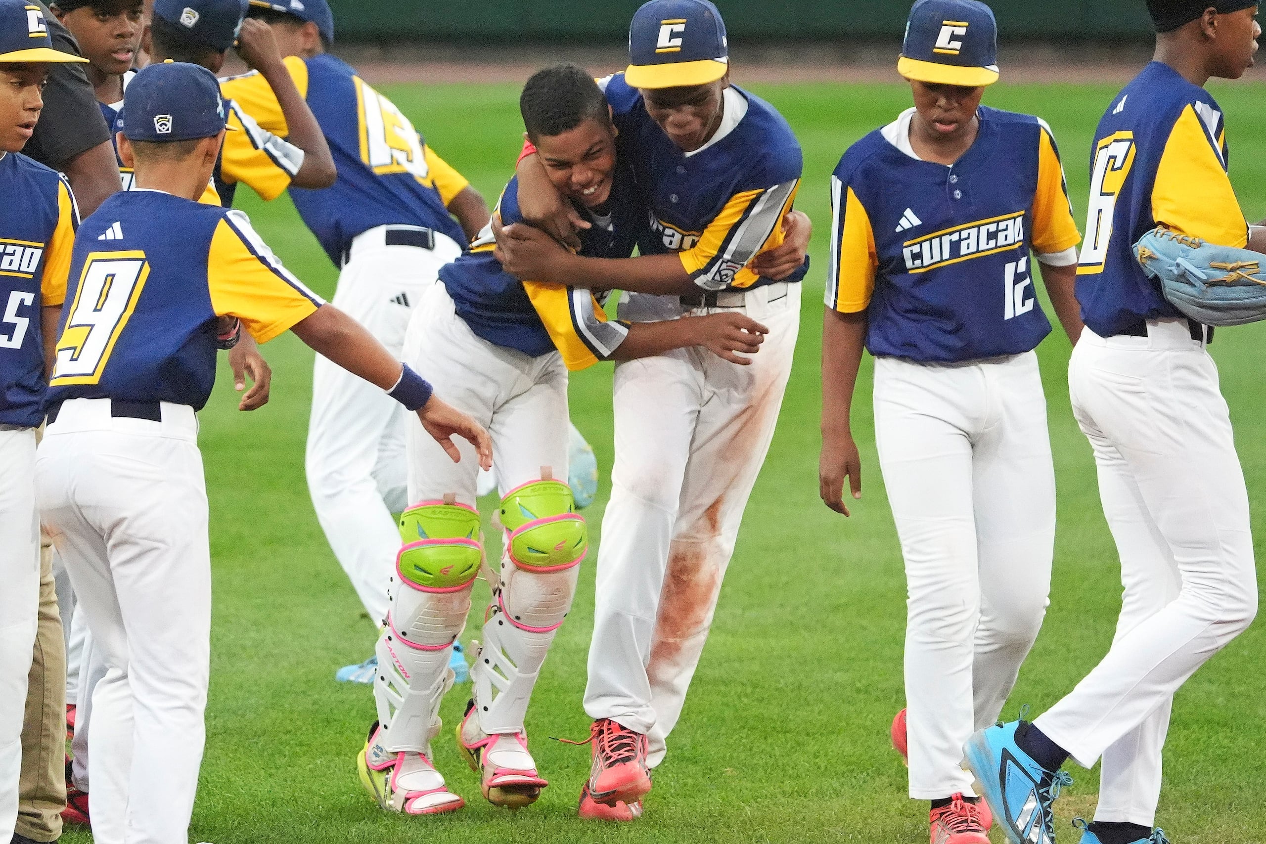 Ignacio Lindo del V-dien de Curaçao's junto al cátcher Naeem Angel Coeriel celebran con el resto del equipo tras ganar la Serie Mundial de Pequeñas Ligas.