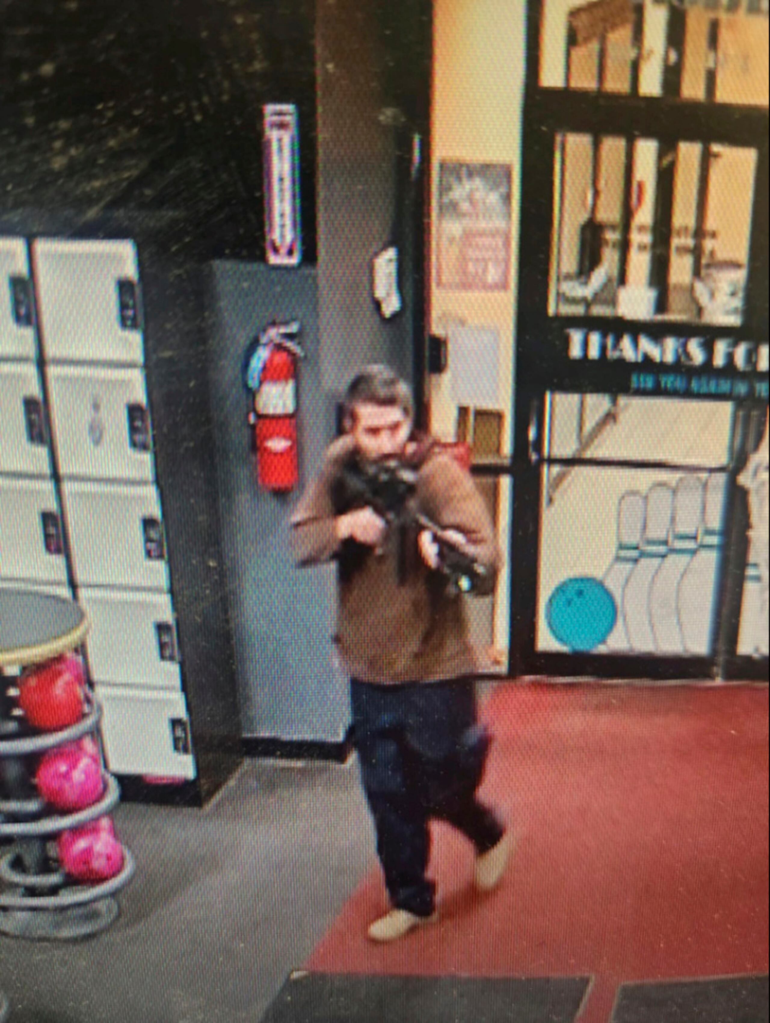 In this image taken from video released by the Androscoggin County Sheriff's Office, an unidentified gunman points a gun while entering Sparetime Recreation in Lewiston, Maine, on Wednesday, Oct. 25, 2023. Maine State Police ordered residents in the state's second-largest city to shelter in place Wednesday night as the suspect remains at large. (Androscoggin County Sheriff's Office via AP)