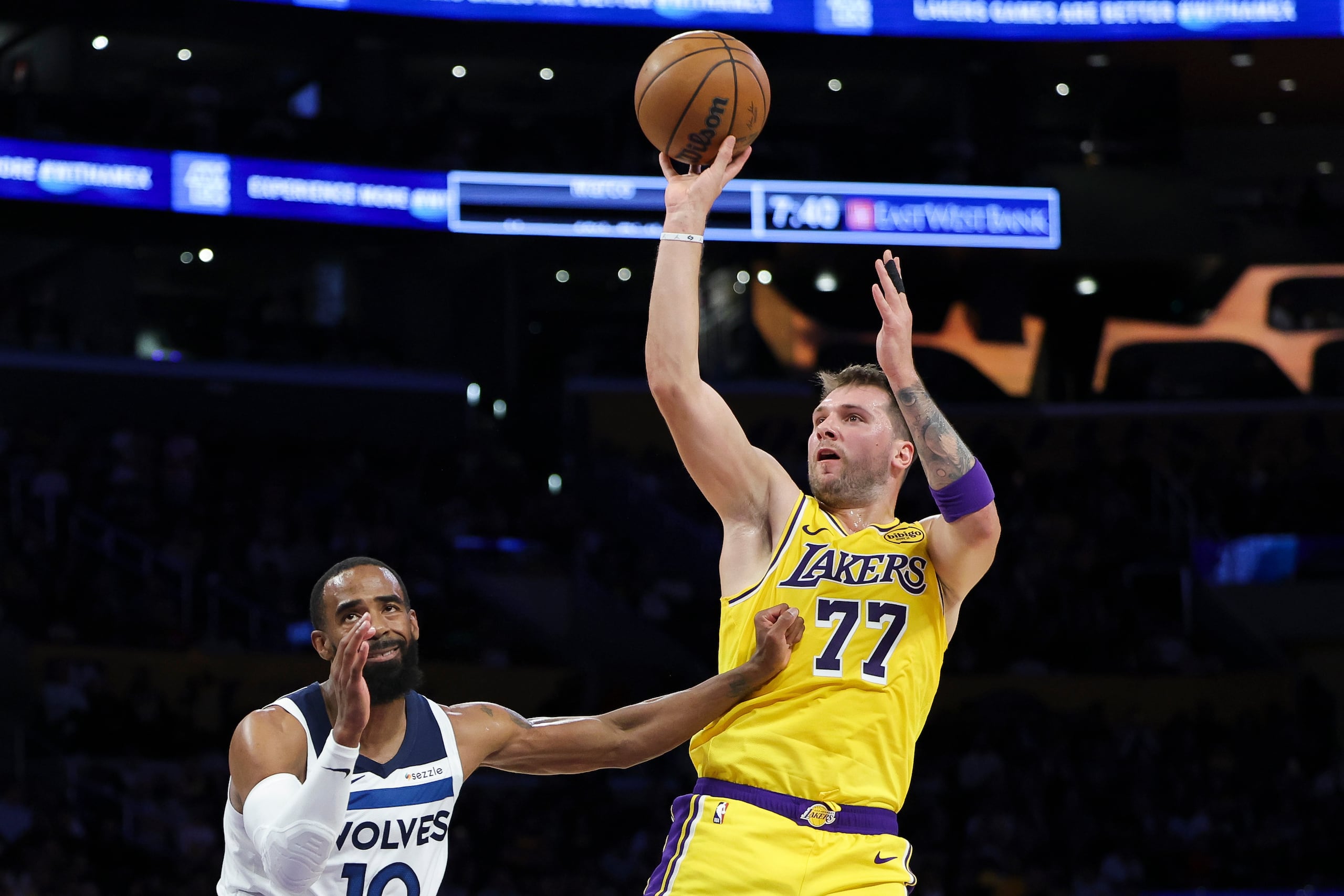 El base de los Lakers de Los Ángeles Luka Doncic lanza el balón frente a Mike Conley de los Timberwolves de Minnesota.
