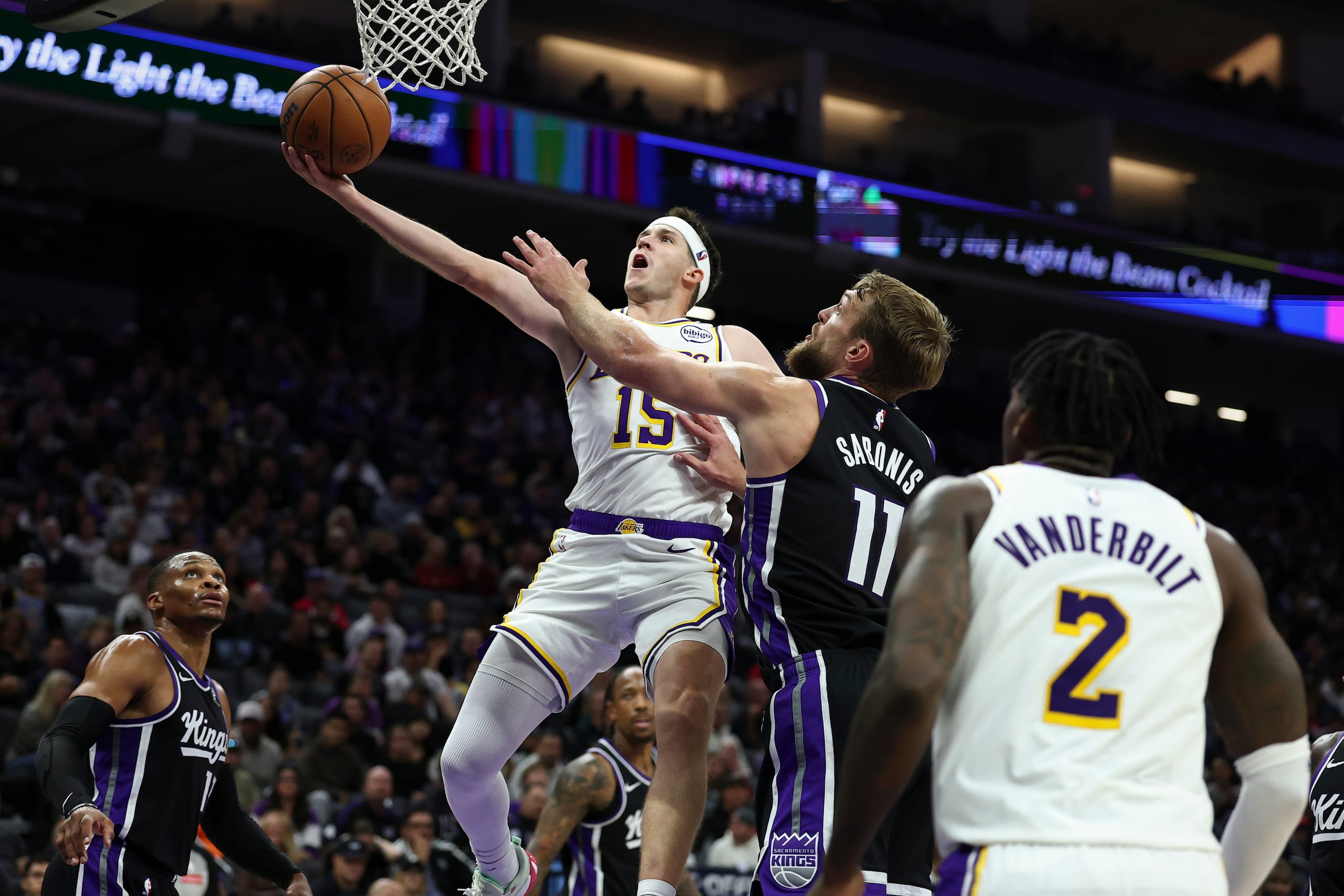 Austin Reaves, izquierda, de los Lakers de Los Ángeles, recibe una falta de Domantas Sabonis (11), de los Kings de Sacramento.