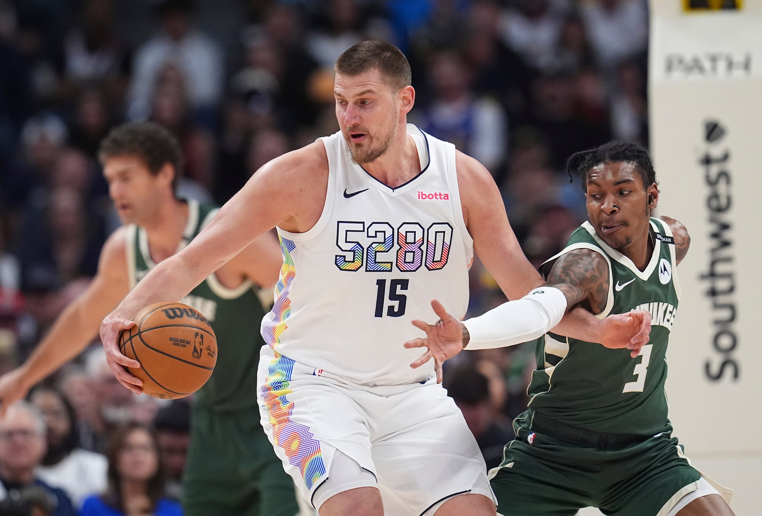 Nikola Jokic (15), de los Nuggets de Denver, toma el balón mientras que Kevin Porter Jr., de los Bucks de Milwaukee, defiende en la primera mitad del juego del miércoles.