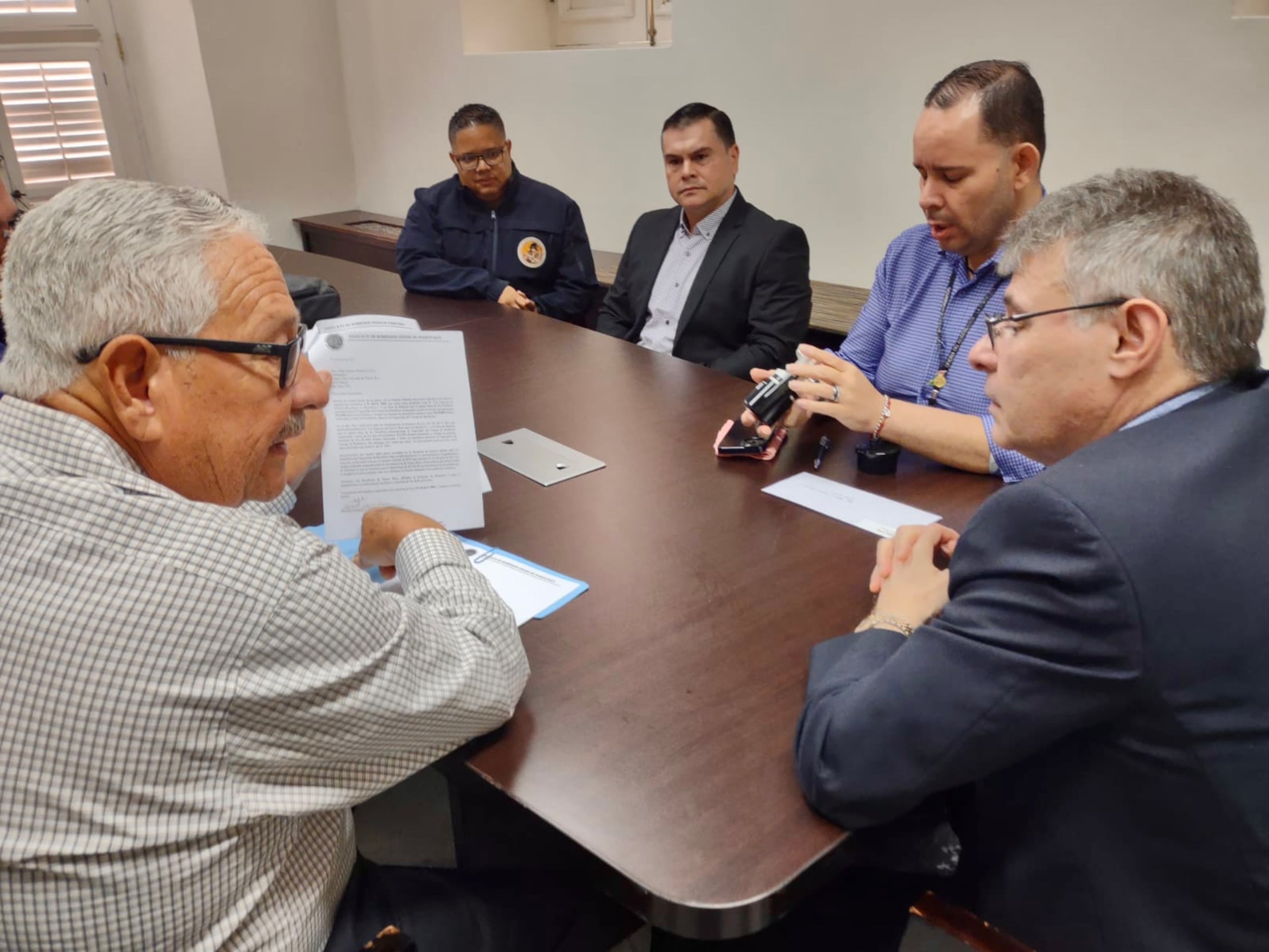 El presidente del Sindicato de Bomberos, José Tirado, le muestra una de las cartas en la que los bomberos exigen su aumento salarial a un asesor del gobernador Pedro Pierluisi.