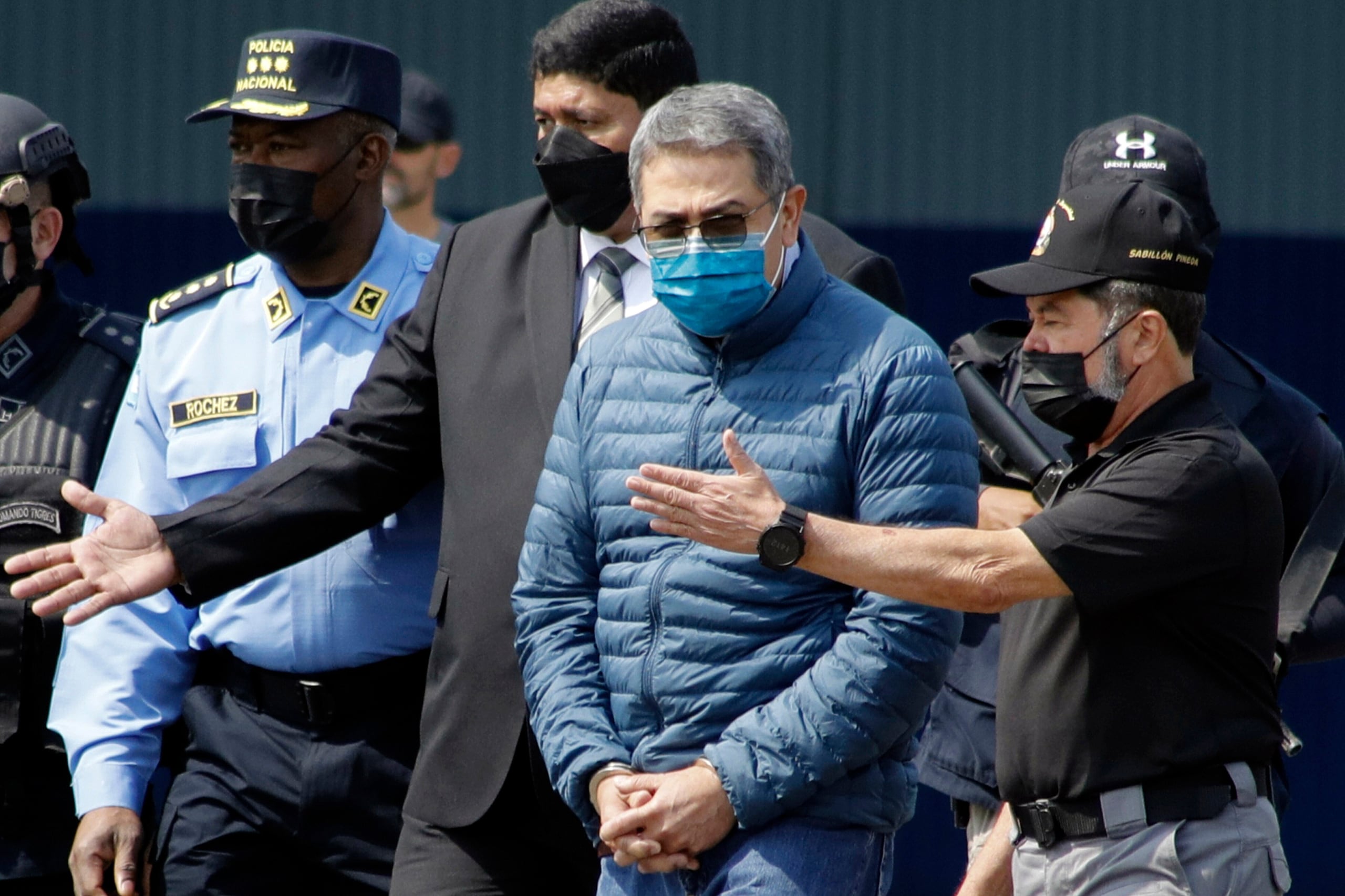 El expresidente hondureño Juan Orlando Hernández, segundo de la derecha, es conducido esposado a un avión que lo espera para su extradición a Estados Unidos, en una base aérea de Tegucigalpa, Honduras, el 21 de abril de 2022. (AP Foto/Elmer Martínez/Archivo)