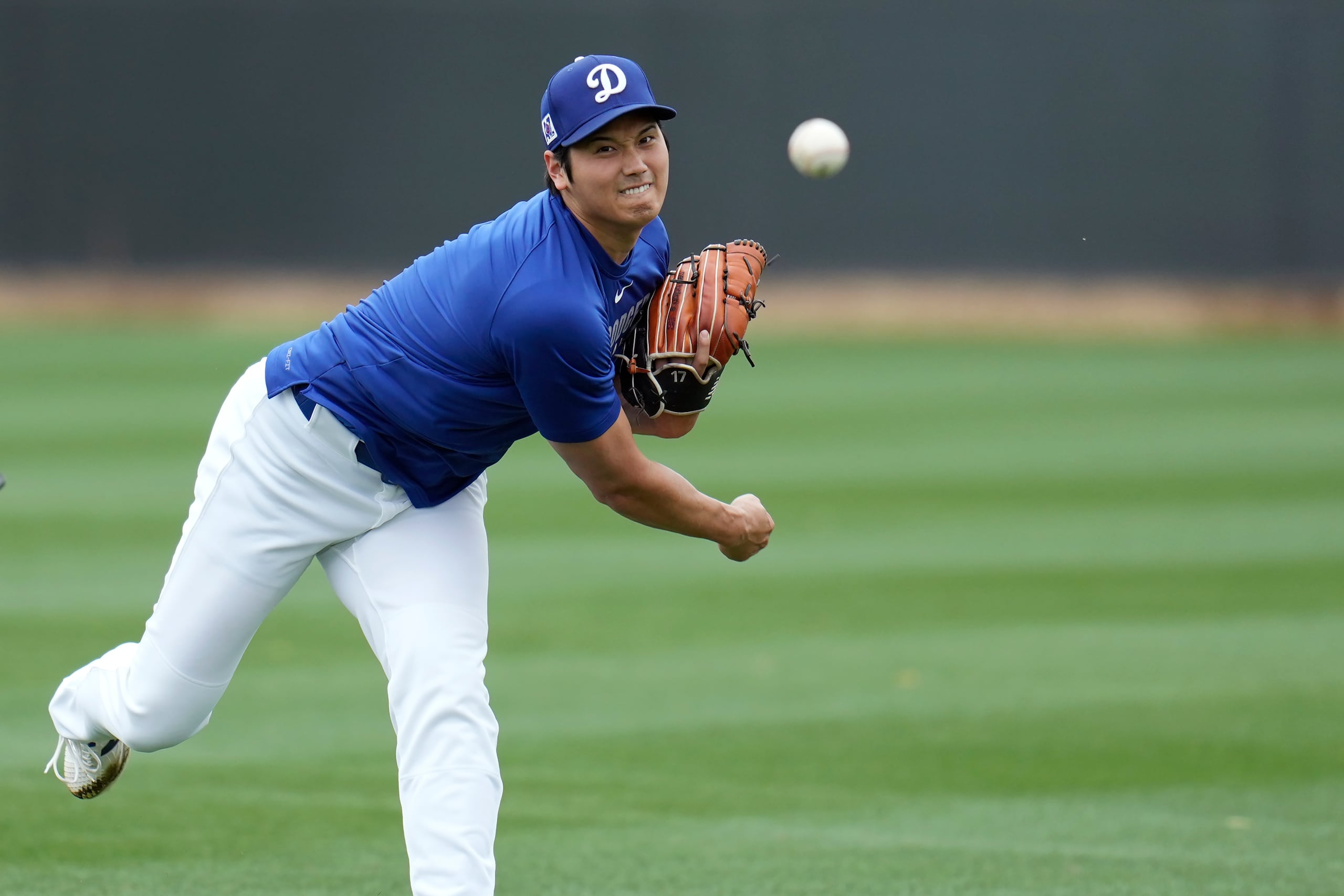 El japonés Shohei Ohtani, de los Dodgers de Los Ángeles, lanza mientras calienta en las instalaciones de entrenamiento de primavera del equipo, el miércoles 12 de febrero de 2025, en Phoenix. (AP Foto/Ross D. Franklin)