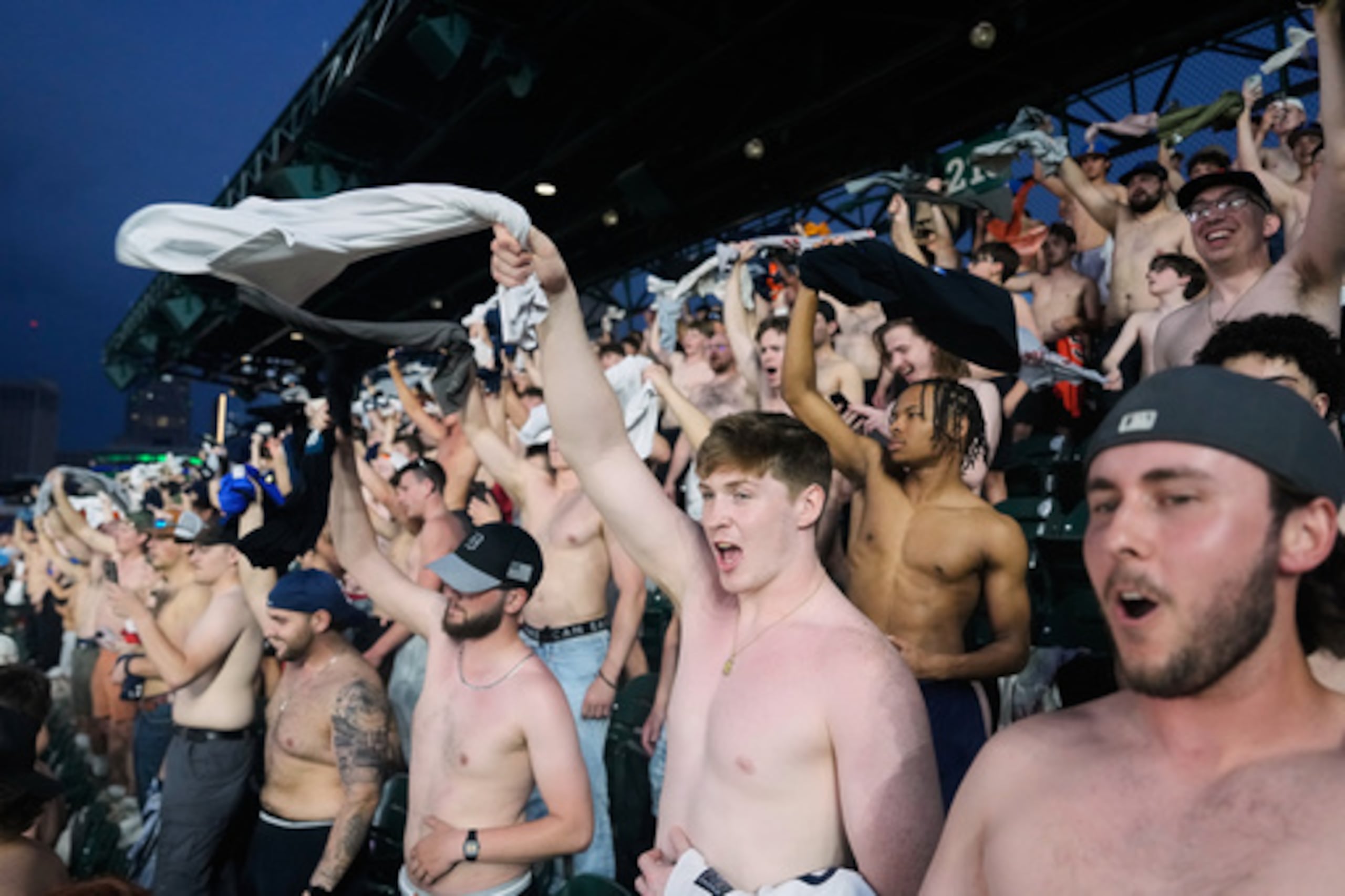 Los aficionados animan sin camiseta después de dirigirse a los asientos de la cubierta superior del campo durante la novena entrada de un partido de béisbol entre los Tigres de Detroit y los Guardianes de Cleveland el martes 19 de mayo de 2026, en Detroit. (AP Photo/Paul Sancya)