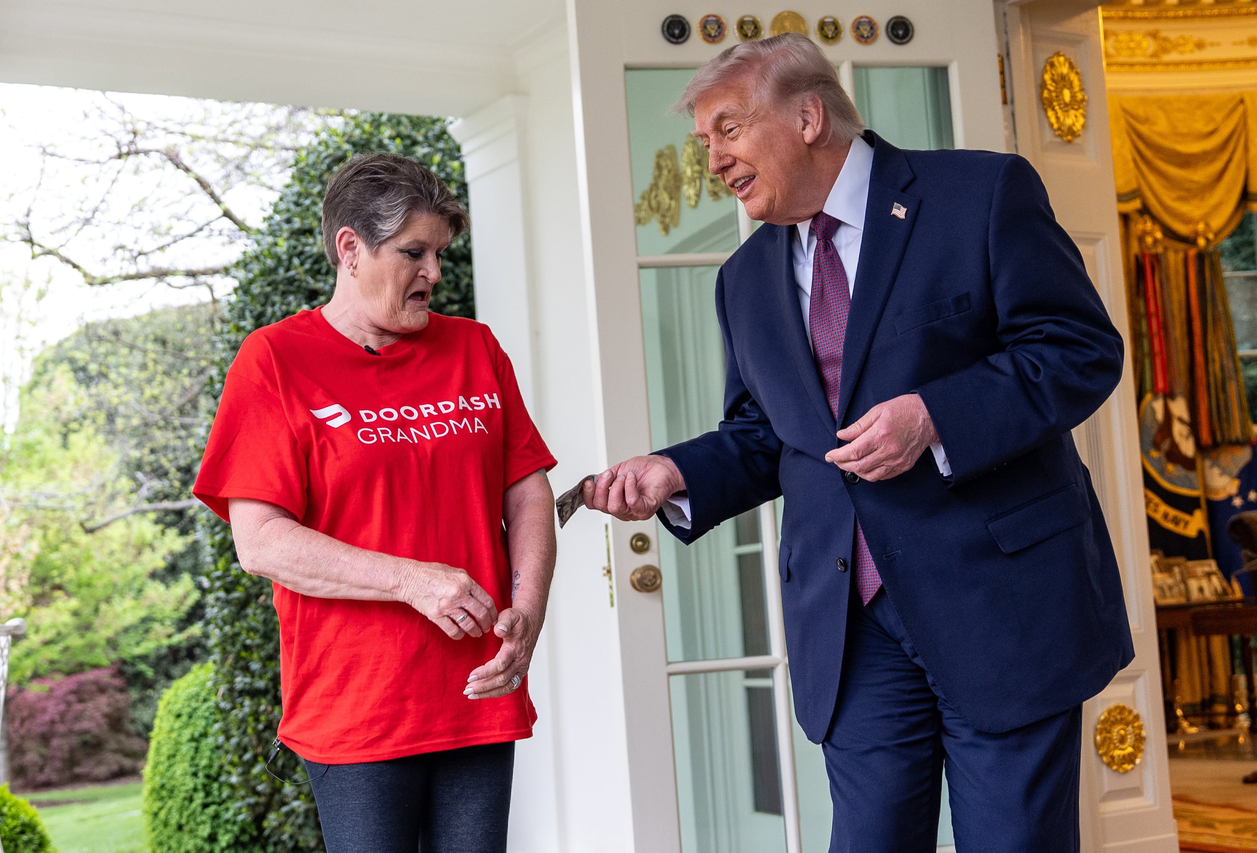 Sharon Simmons, repartidora de DoorDash, recibe una propina después de llevarle un pedido de McDonald's al presidente Donald Trump en el Despacho Oval de la Casa Blanca, el lunes 13 de abril de 2026, en Washington. (AP Foto/Alex Brandon)
