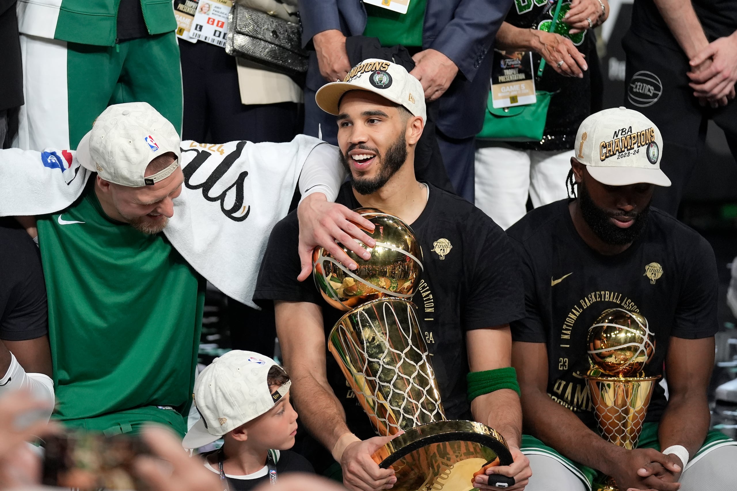 Jayson Tatum, al centro, sostiene el trofeo Larry O'Brien mientras celebra con Kristaps Porzingis, izquierda, y Jaylen Brown, derecha, el campeonato que ganaron hace un par de semana.