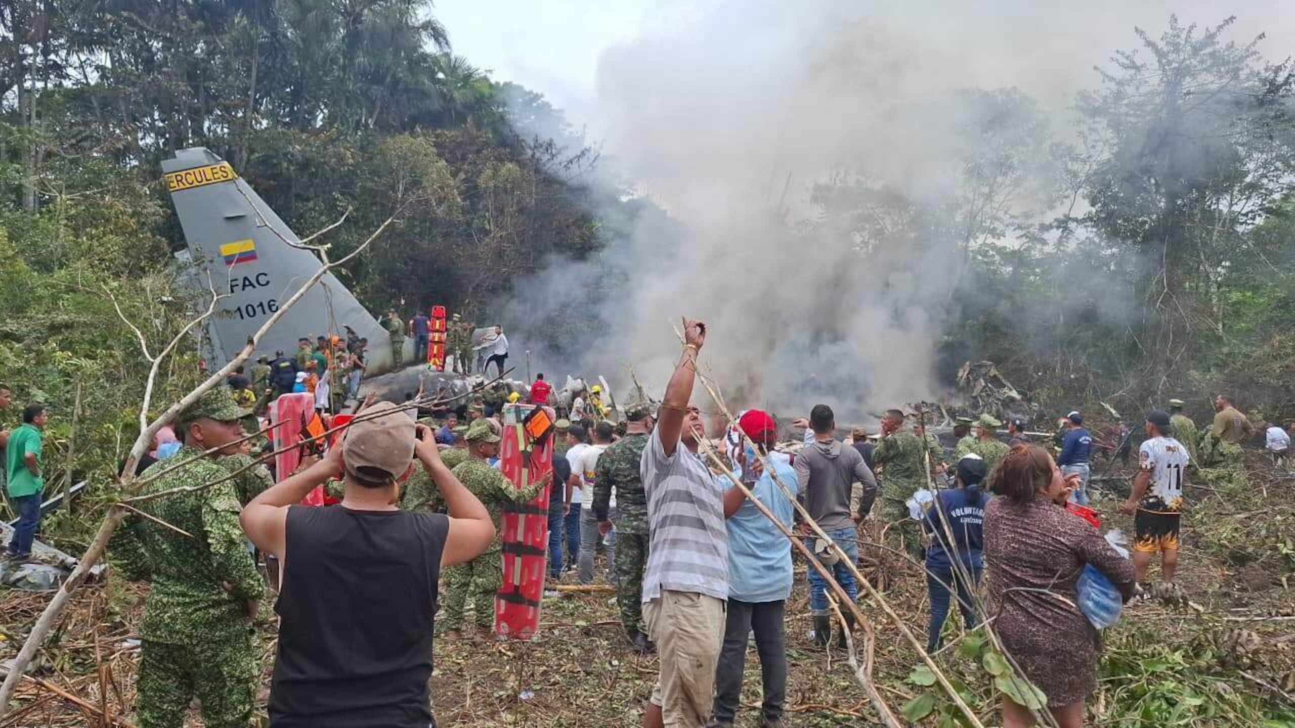 La gente se agrupa alrededor de un avión militar de carga que se estrelló tras despegar de Puerto Leguizamo, Colombia, un remoto municipio en la provincia amazónica de Putumayo, el lunes 23 de marzo de 2026. (MiPutumayo vía AP)