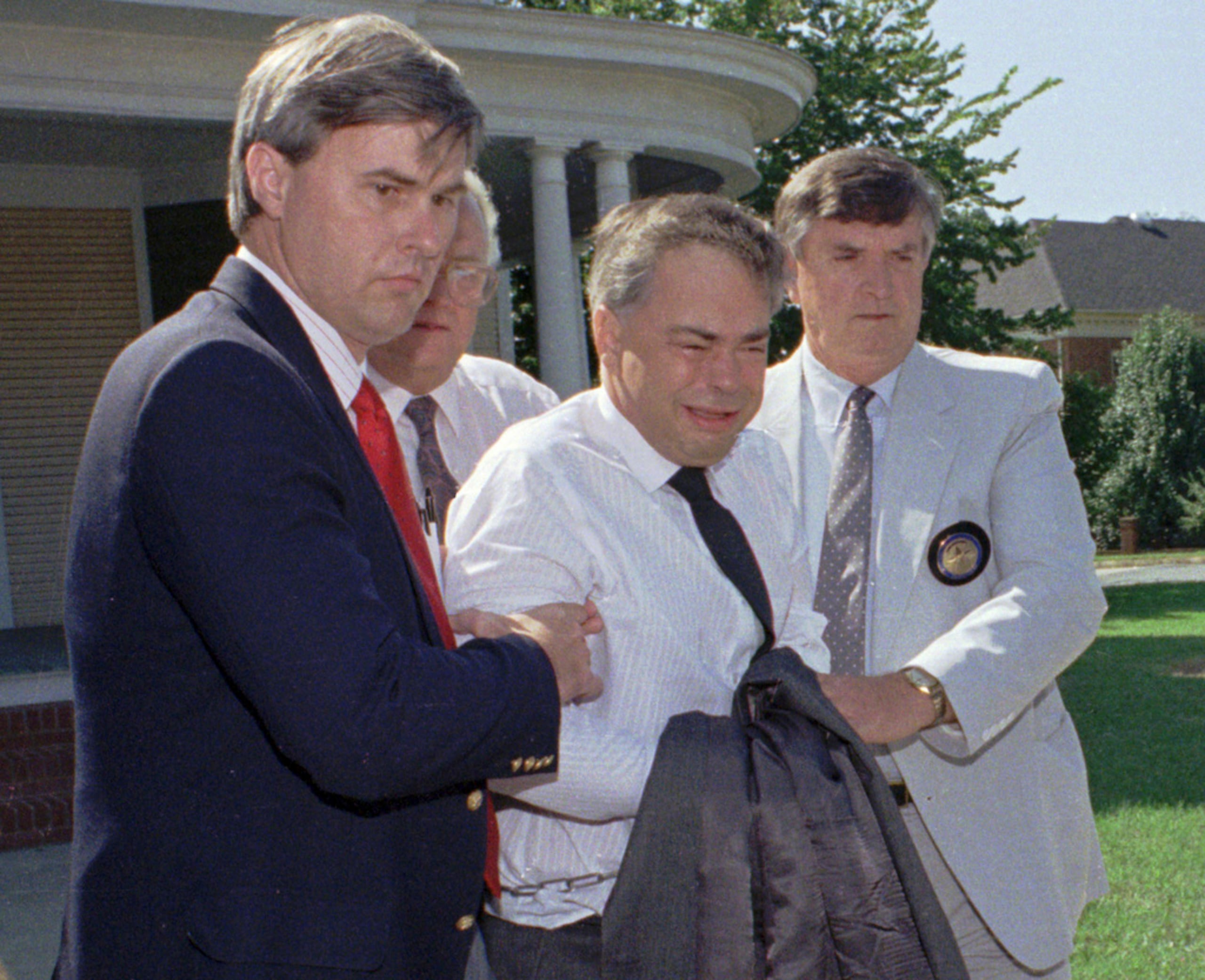 Alguaciles federales escoltan al exlíder del ministerio PTL, Jim Bakker, al centro, desde la oficina de su abogado hasta un auto que lo esperaba, el 31 de agosto de 1989, en Charlotte, Carolina del Norte.