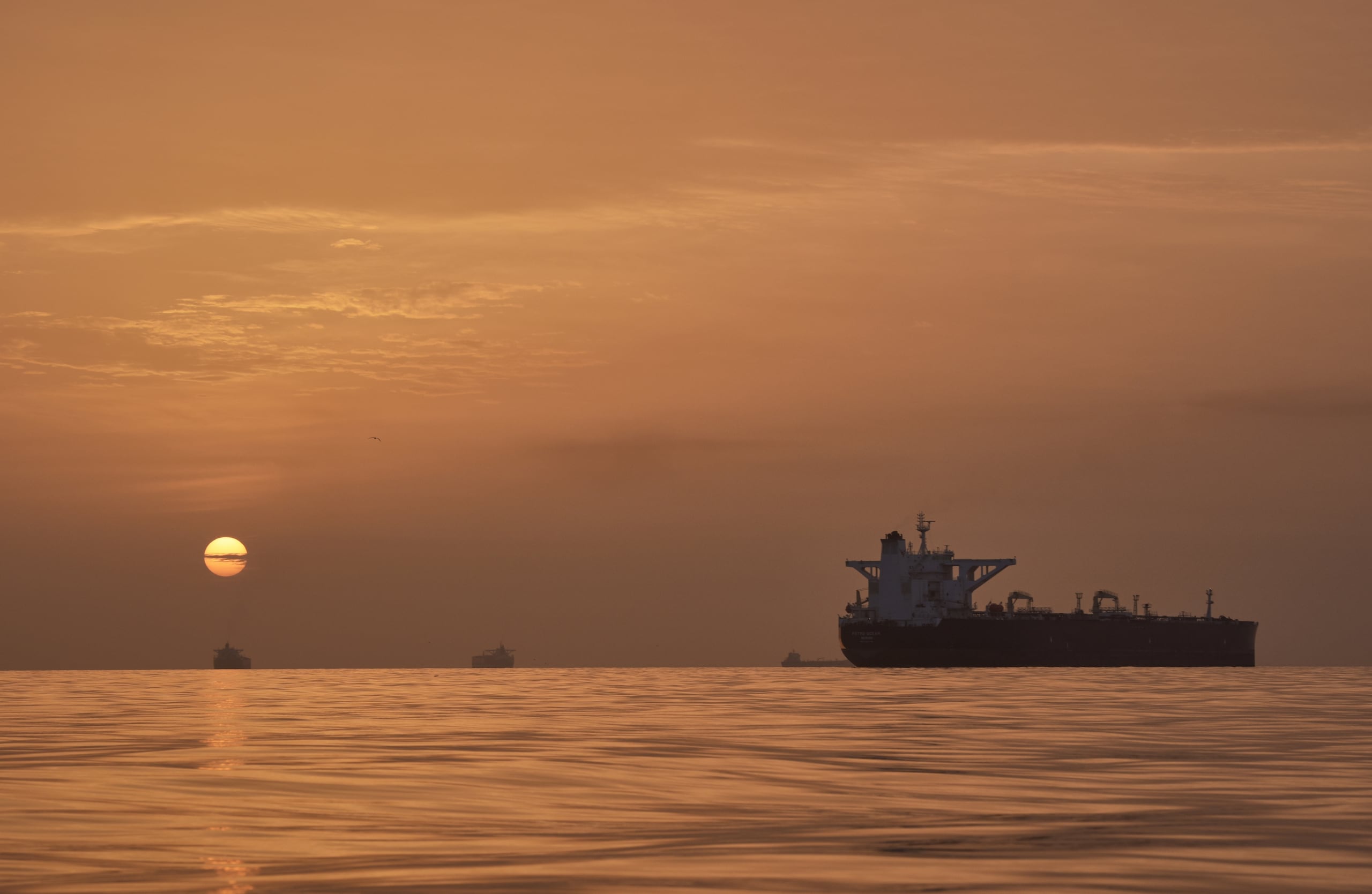 El sol sale tras varios petroleros fondeados en el estrecho de Ormuz en la costa de la isla de Queshm, Irán, el sábado 18 de abril de 2026. (AP Foto/Asghar Besharati)