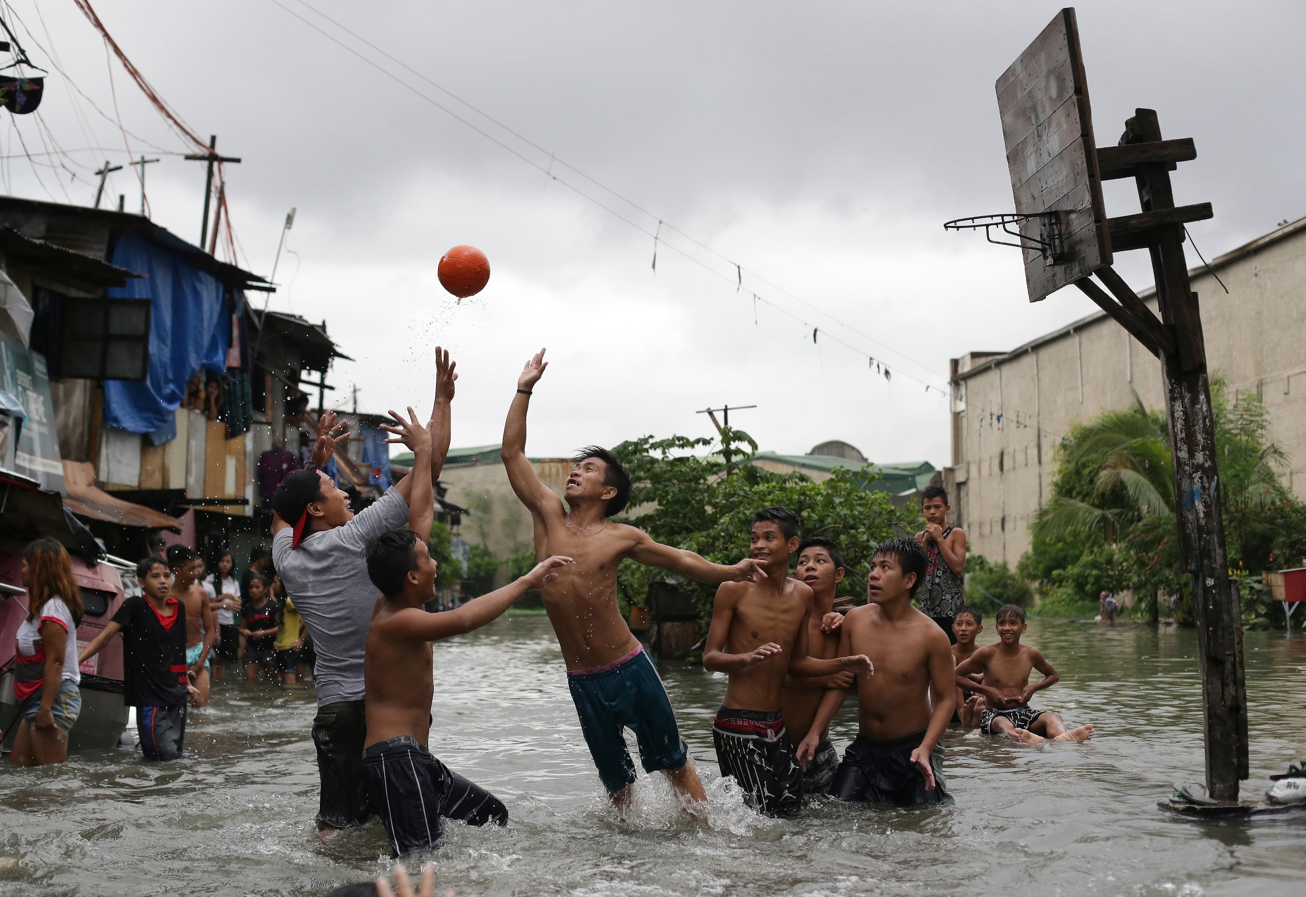 Niños filipinos juegan baloncesto hasta en una improvisada e inundada cancha.