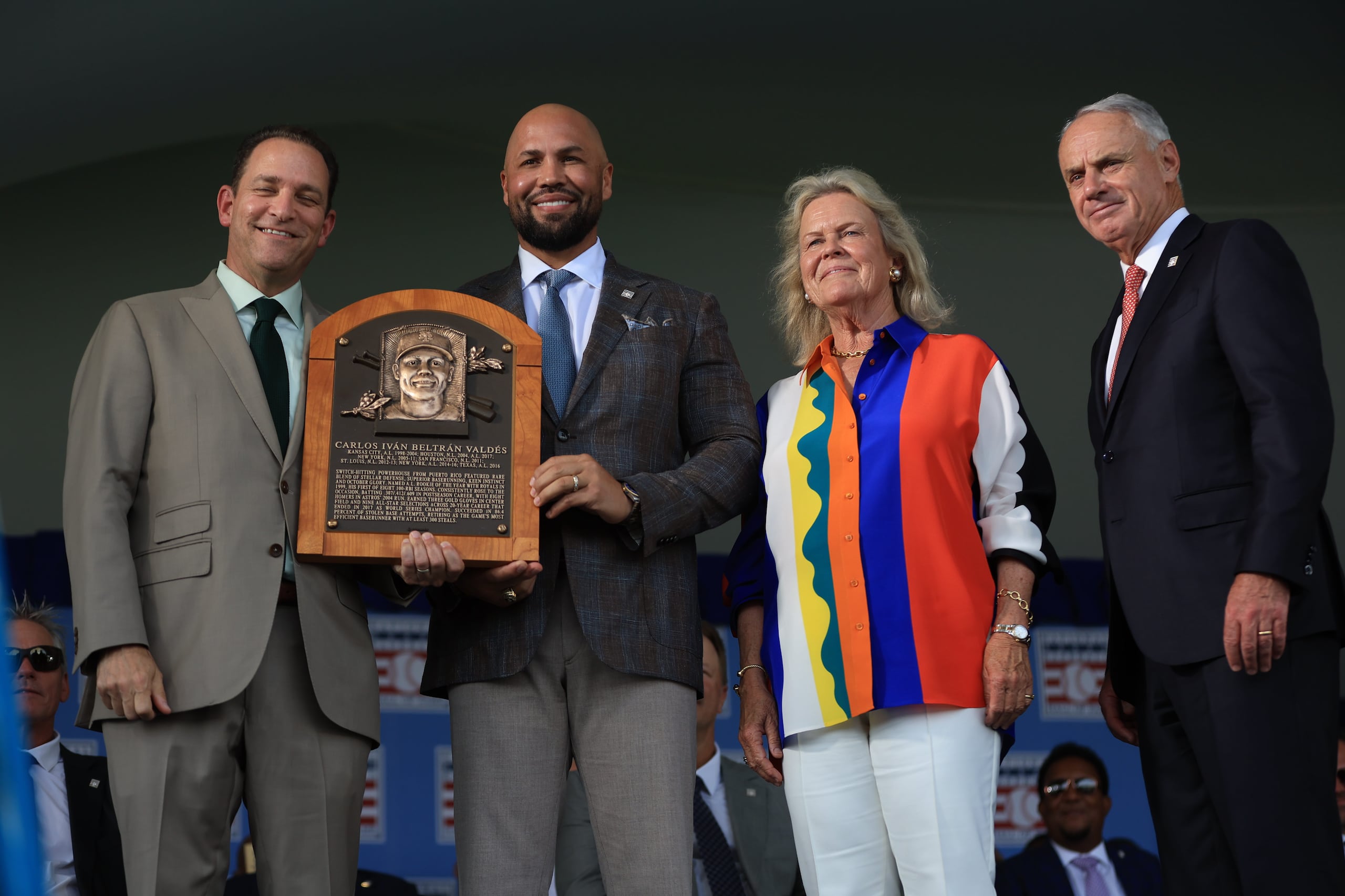 Carlos Beltrán (al centro) posa con la placa que lo acredita como inmortal del Salón de la Fama en Cooperstown.