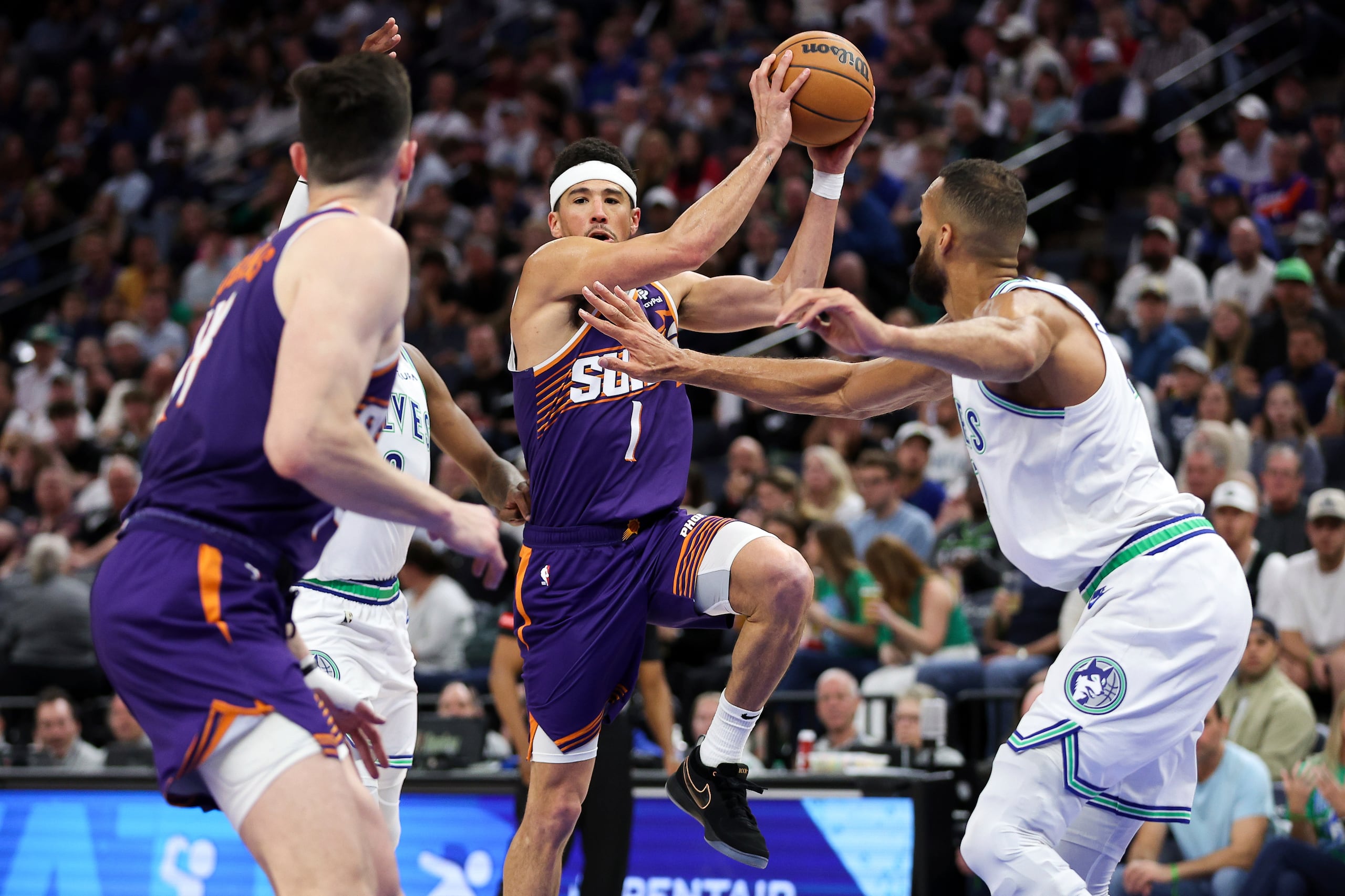 El escolta de los Suns de Phoenix, Devin Booker (1), avanza hacia la canasta mientras el pívot de los Timberwolves de Minnesota, Rudy Gobert, a la derecha, defiende durante la segunda mitad del partido de baloncesto de la NBA, el domingo 14 de abril de 2024, en Minneapolis. (AP Foto/Matt Krohn)