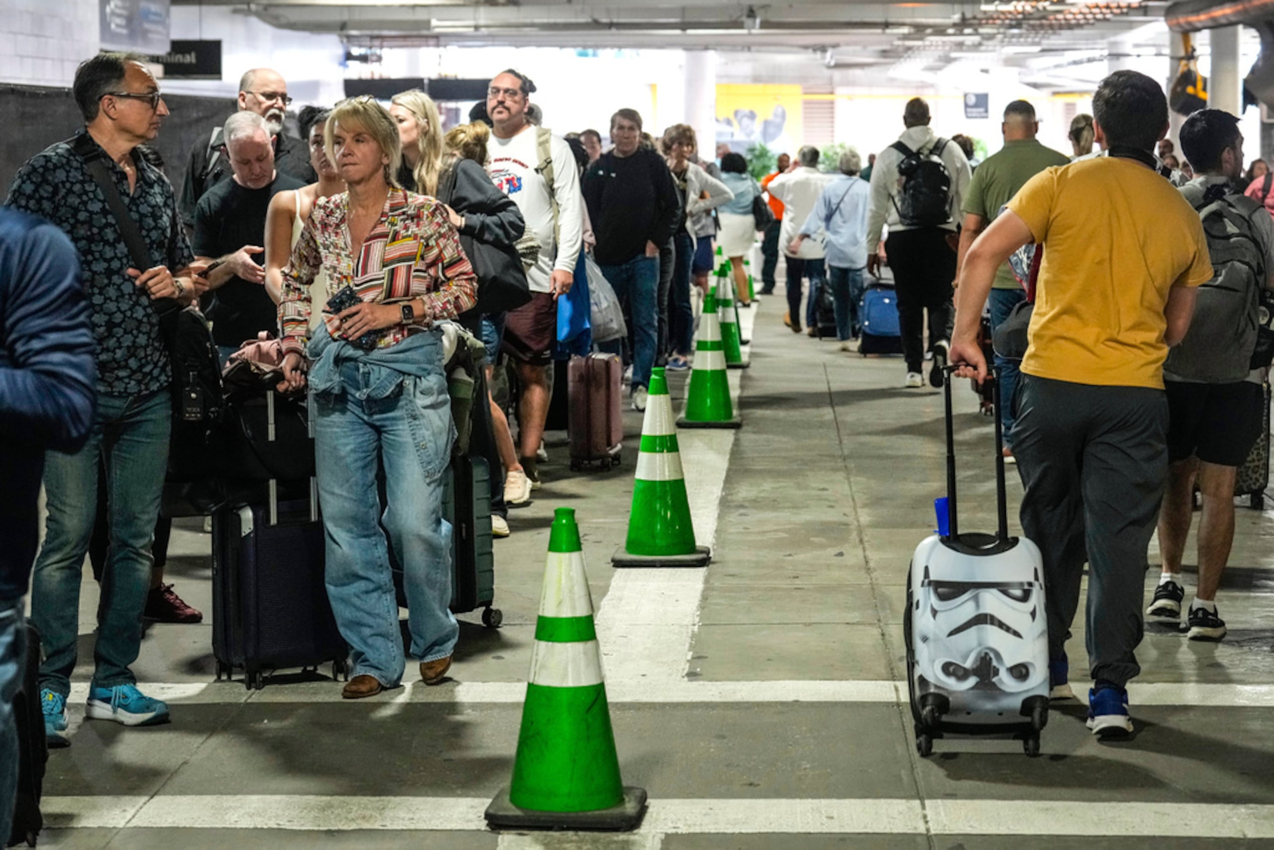 Pasajeros de aerolínea esperan en largas filas fuera de la terminal, incluso en el estacionamiento, para pasar por el control de seguridad de TSA en el Aeropuerto William P. Hobby en Houston, el domingo 8 de marzo de 2026.