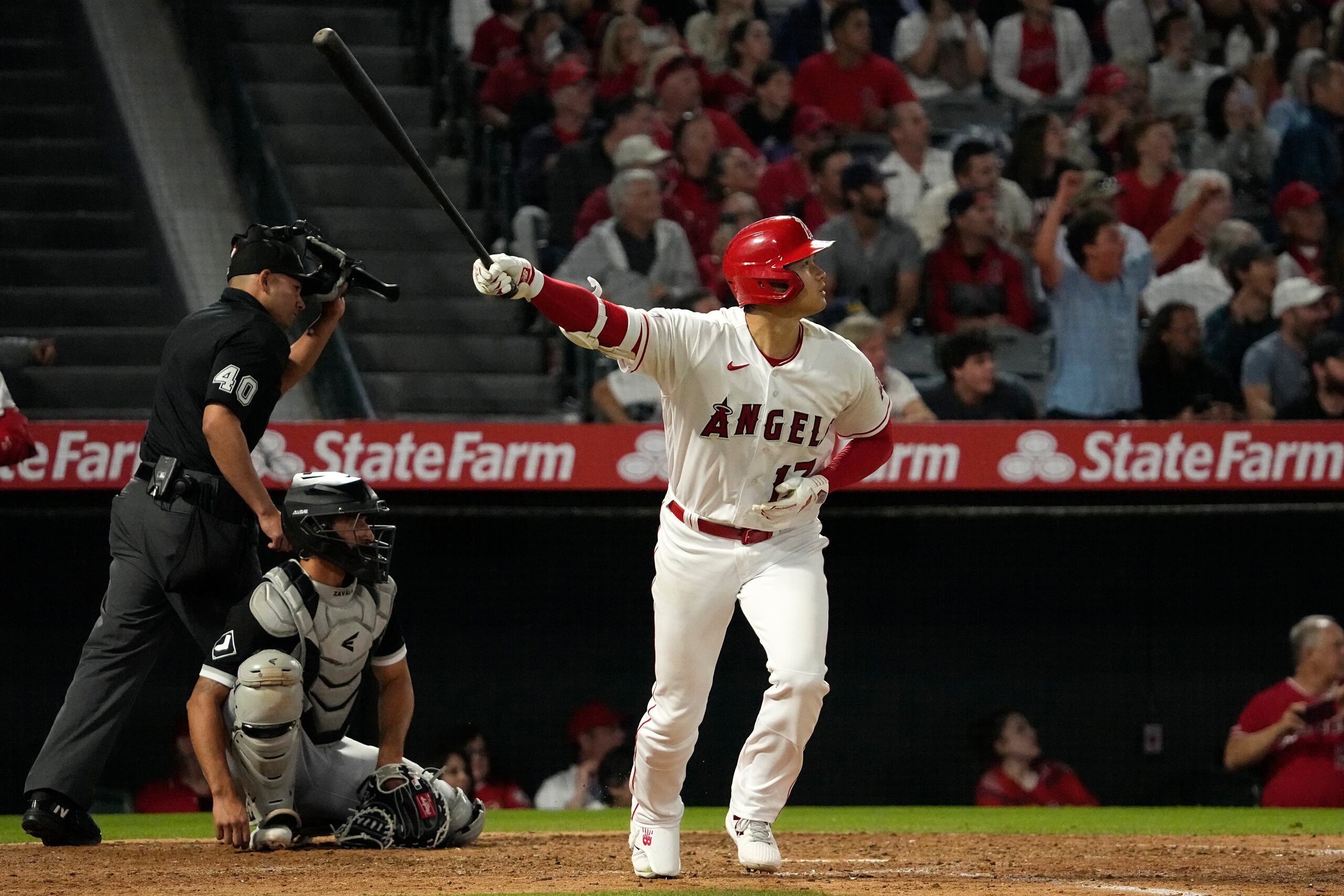Shohei Ohtani de los Angels de Los Ángeles avanza a primera tras conectar un jonrón frente al cátcher de los Medias Blancas de Chicago Yasmani Grandal y el umpire Roberto Ortiz en la séptima entrada del juego del martes 27 de junio del 2023.