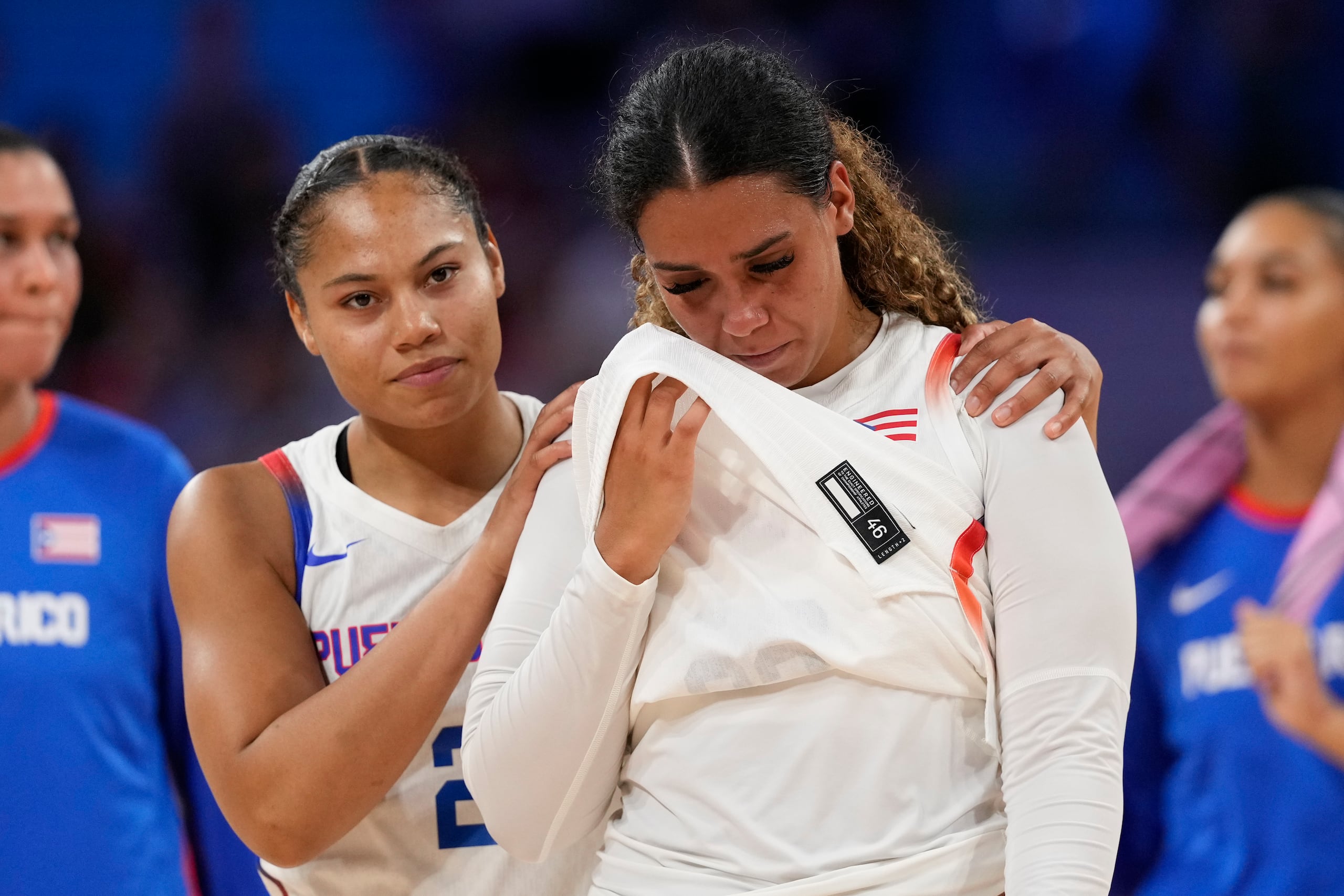 Brianna Jones, a la izquierda, consuela a India Pagán, de Puerto Rico,  mientras salen de la cancha del doloroso revés.