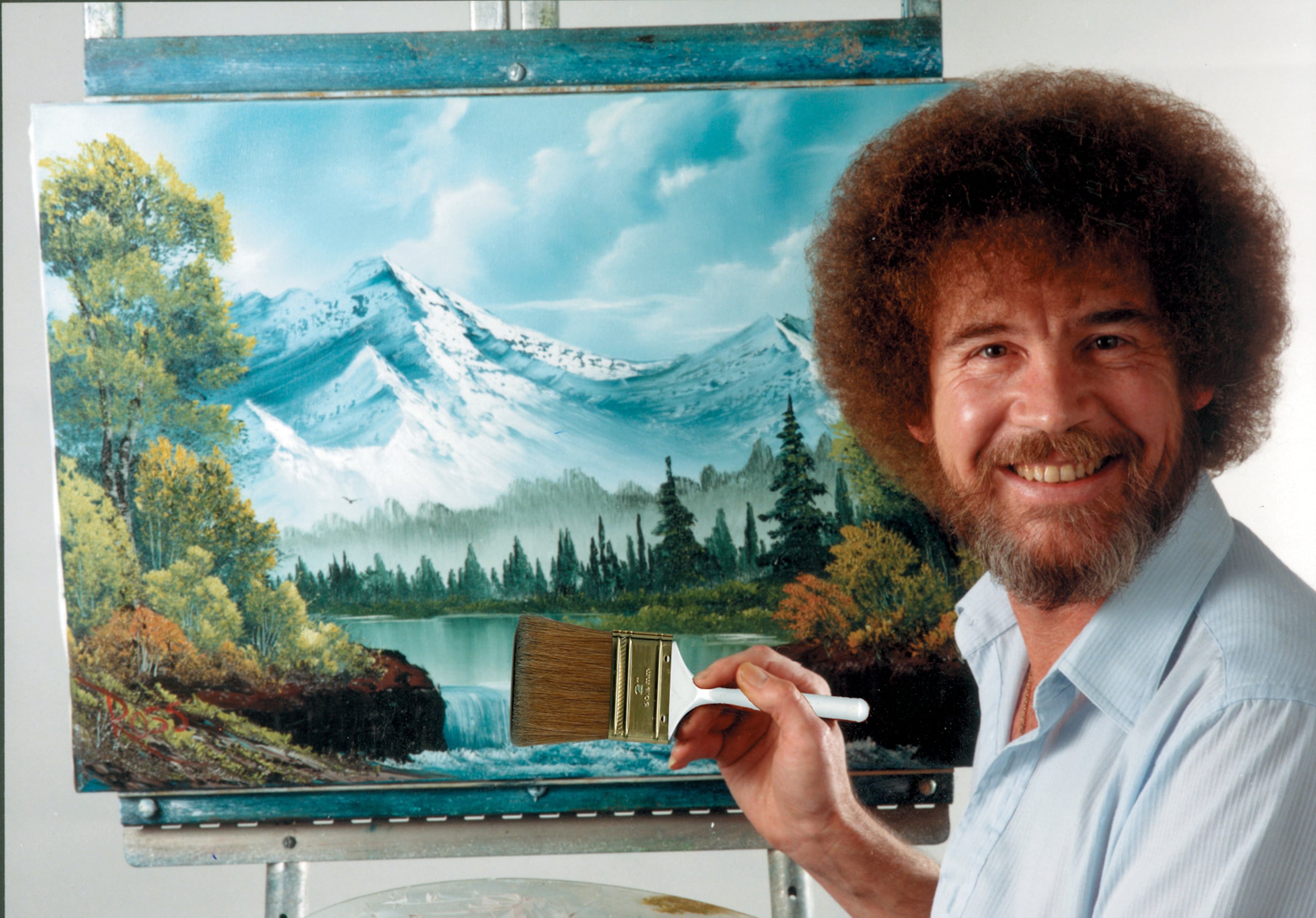 En esta imagen difundida por Bob Ross Inc., Bob Ross posa para una fotografía frente a una de sus obras. (Bob Ross Inc. vía AP)