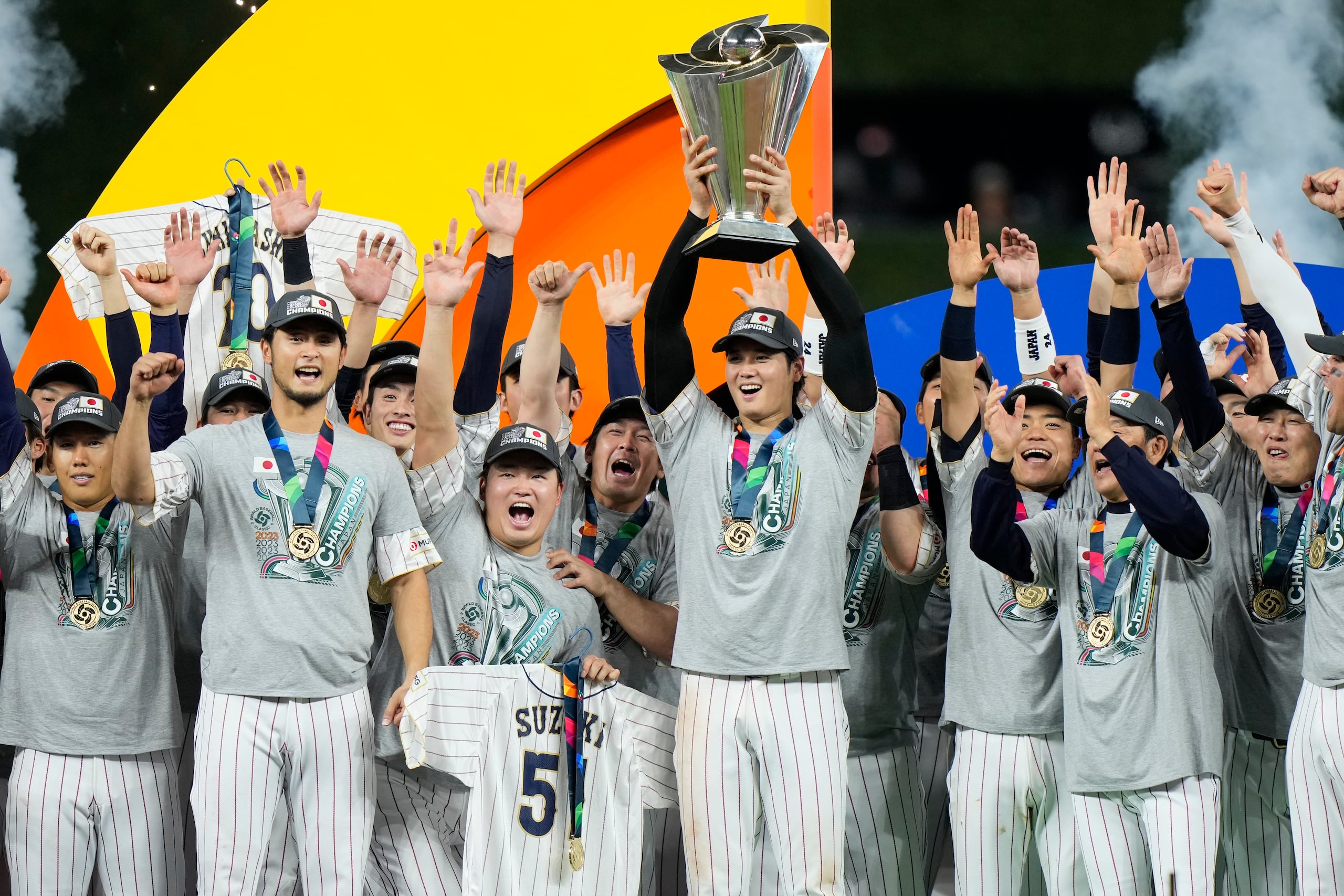 El lanzador Shohei Ohtani, Jugador Más Valioso de la final del Clásico Mundial de Béisbol 2023, levanta el trofeo de campeón rodeado de sus compañeros del equipo de Japón.