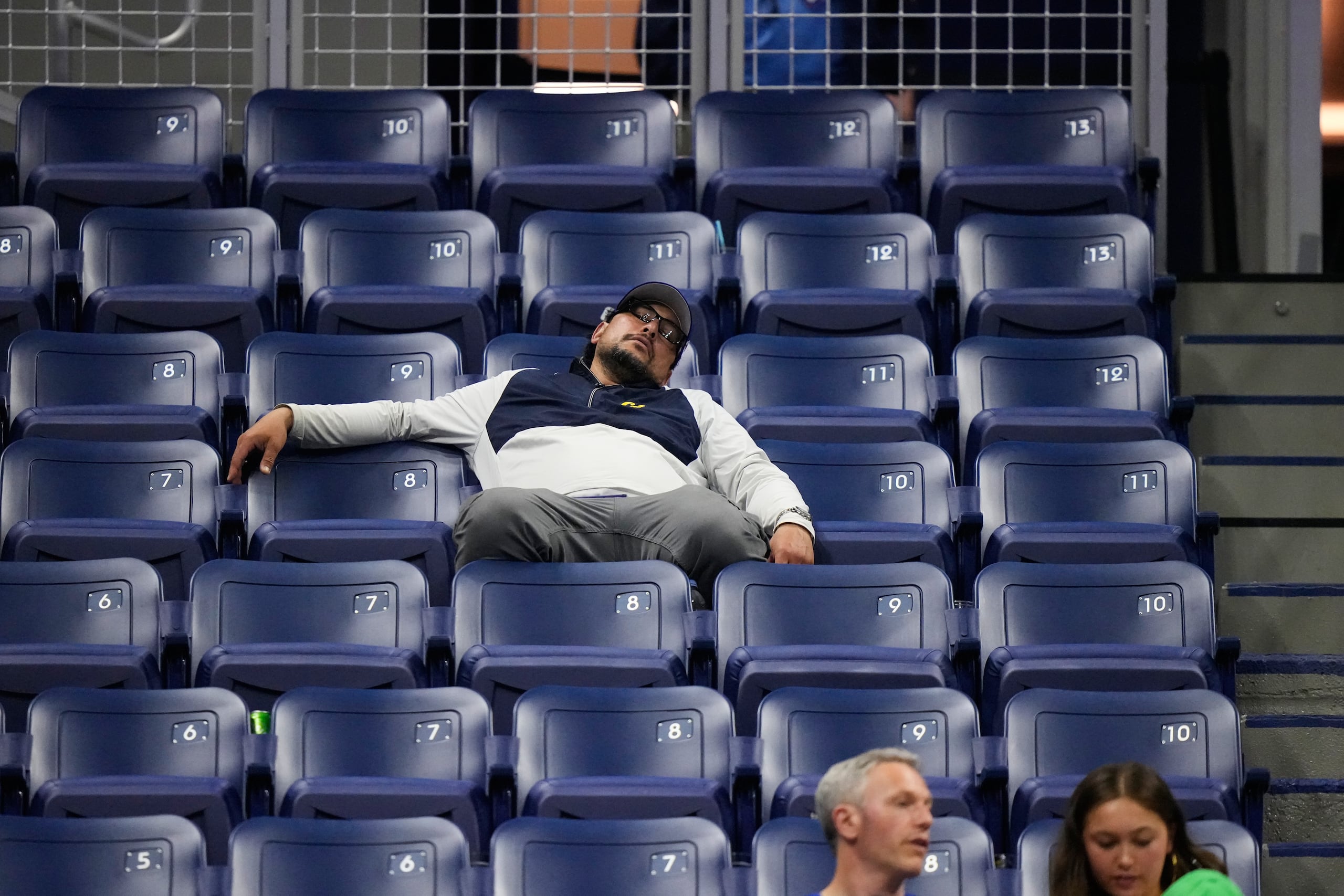 Un espectador duerme en su asiento mientras el alemán Alexander Zverev se enfrenta al chileno Alejandro Tabil.
