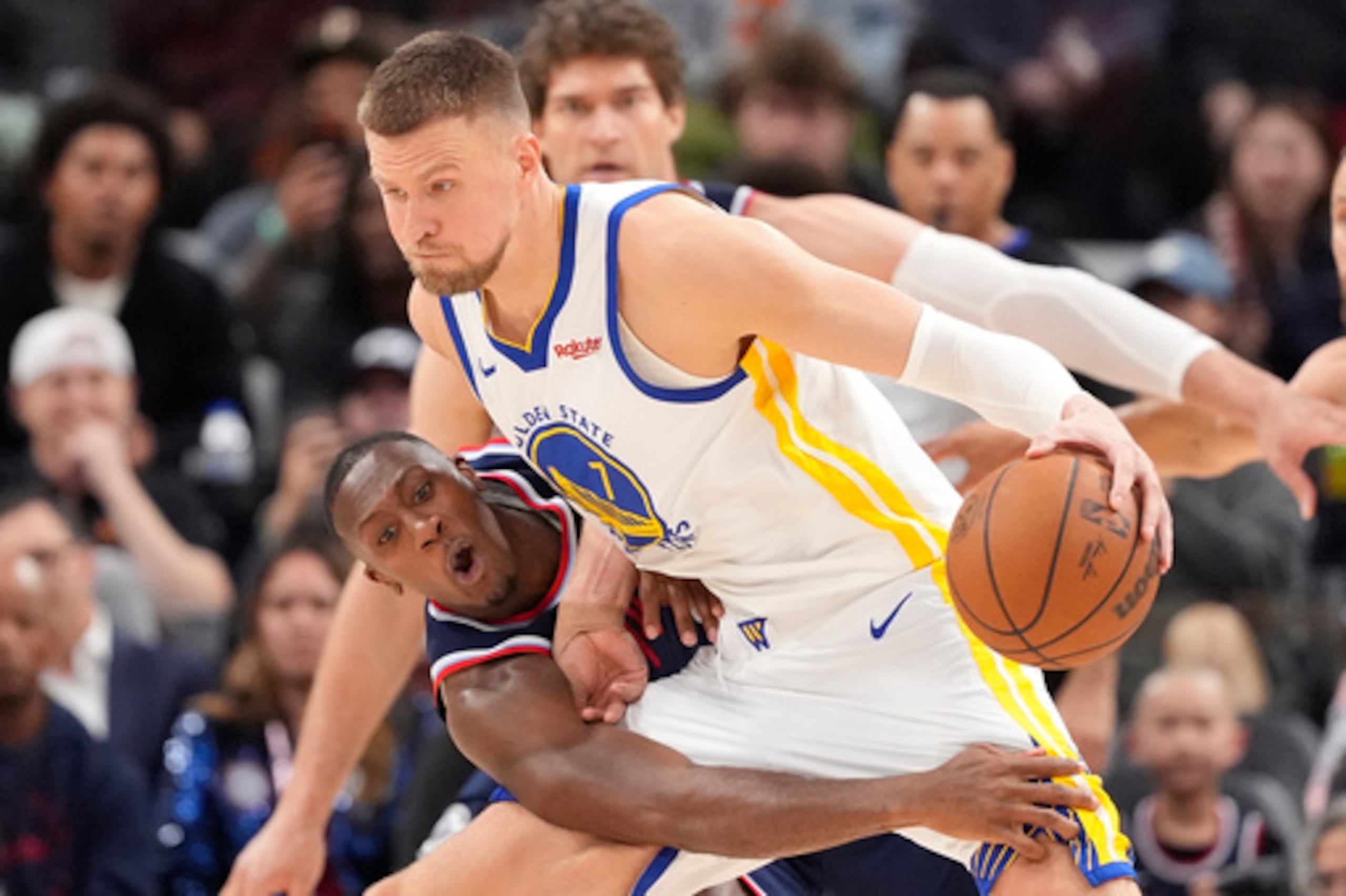 El base de los Clippers de Los Ángeles intenta alcanzar el balón de Kristaps Porzingis, de los Warriors de Golden State, en el partido del miércoles 15 de abril de 2026. (Foto AP/Mark J. Terrill)