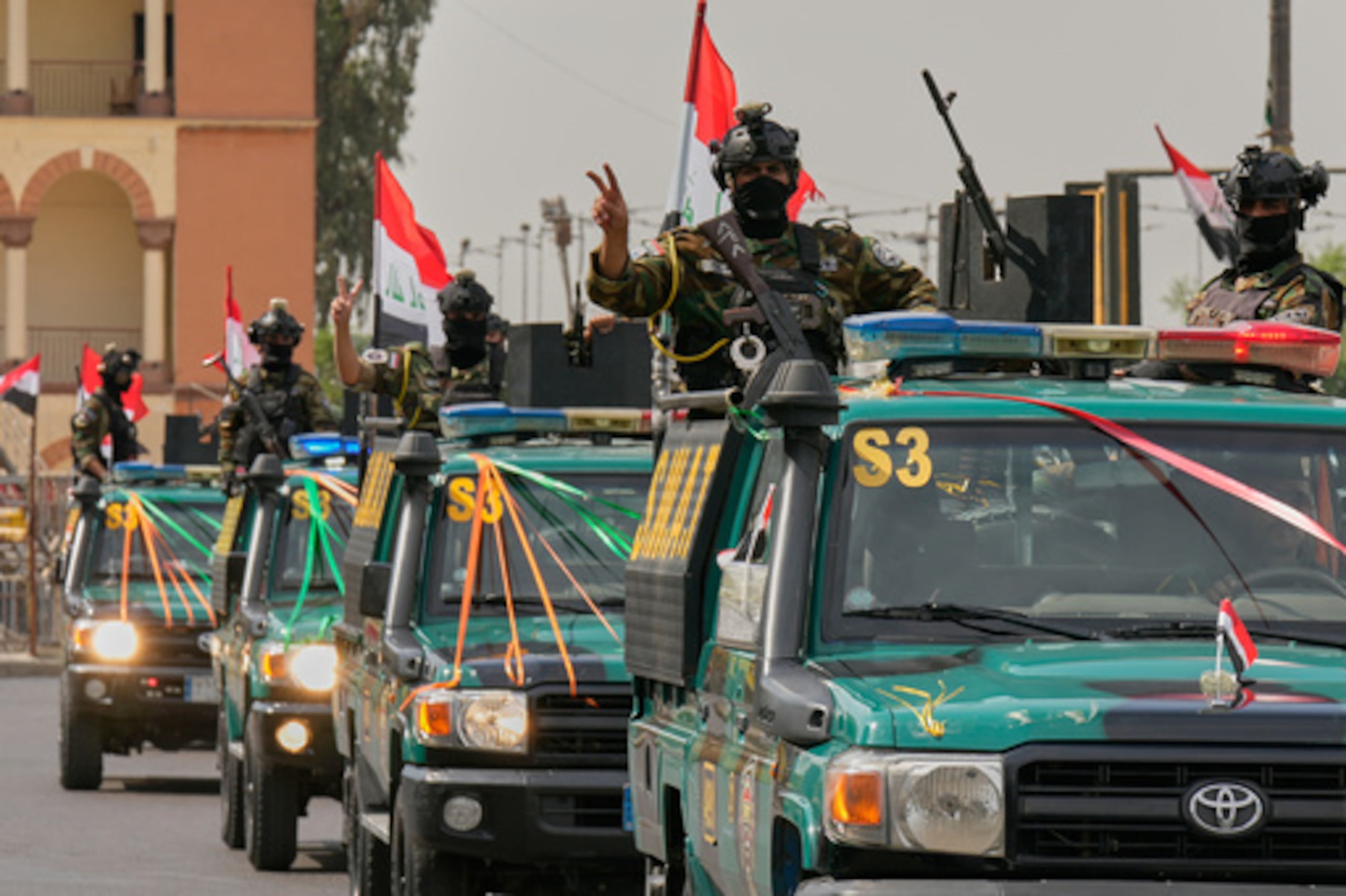 Agentes de las fuerzas de seguridad iraquíes hacen el signo de la victoria con la mano mientras circulan en vehículos decorados con banderas y lazos en una caravana que conmemora la finalización de la retirada de las tropas estadounidenses de Irak, en Bagdad, Irak, el 30 de septiembre de 2026. (Foto AP/Hadi Mizban)