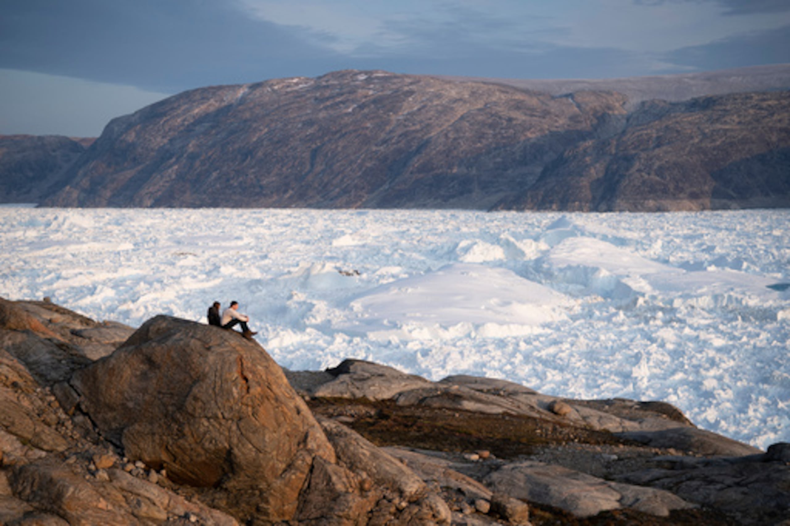 ARCHIVO - Unos estudiantes investigadores de la NYU sentados sobre una roca con vistas al glaciar Helheim, en Groenlandia, el 16 de agosto de 2019. (Foto AP/Felipe Dana, archivo)