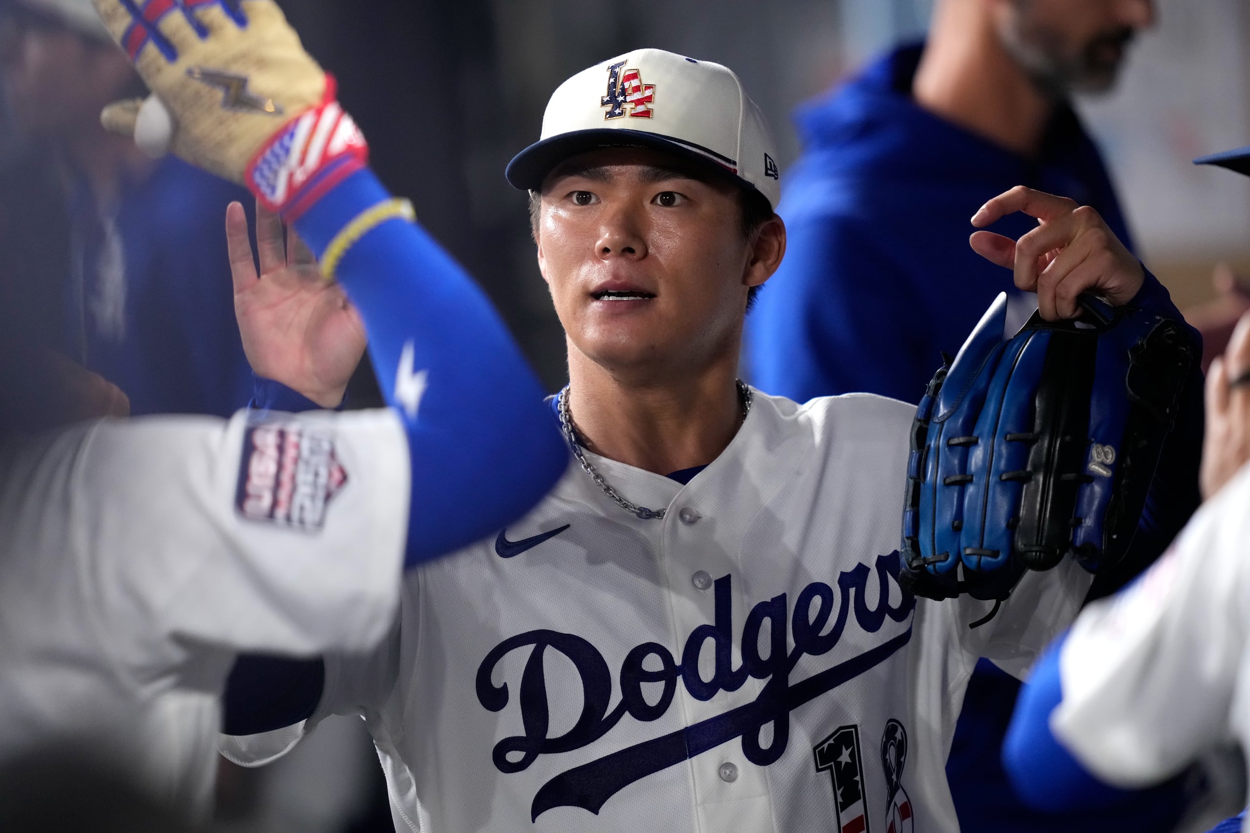 Yoshinobu Yamamoto es felicitado por sus compañeros en el dugout.