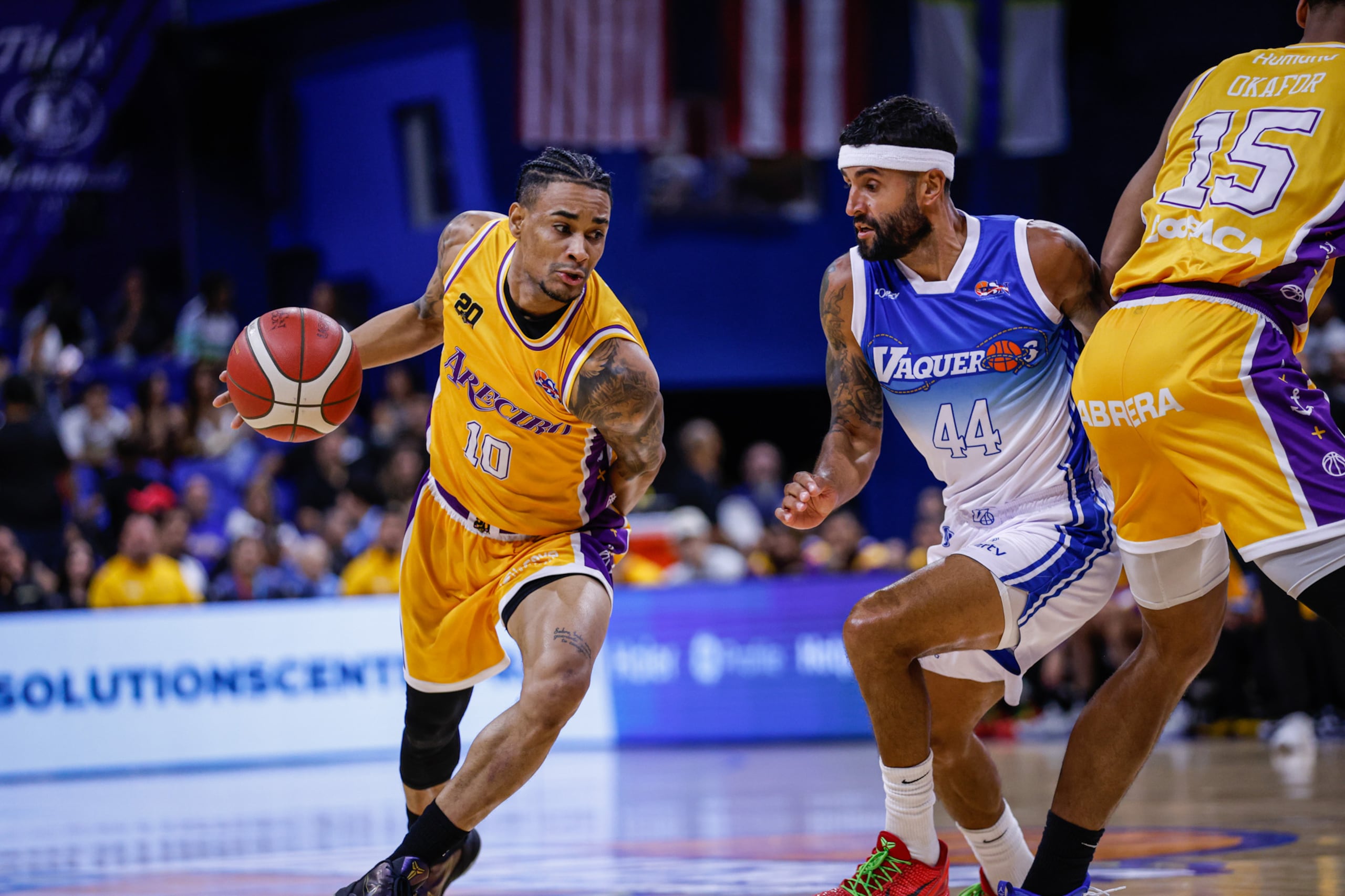 Víctor Liz, en el uniforme de los Capitanes de Arecibo, maneja el balón ante la presión de Javier Mojica, de los Vaqueros de Bayamón.