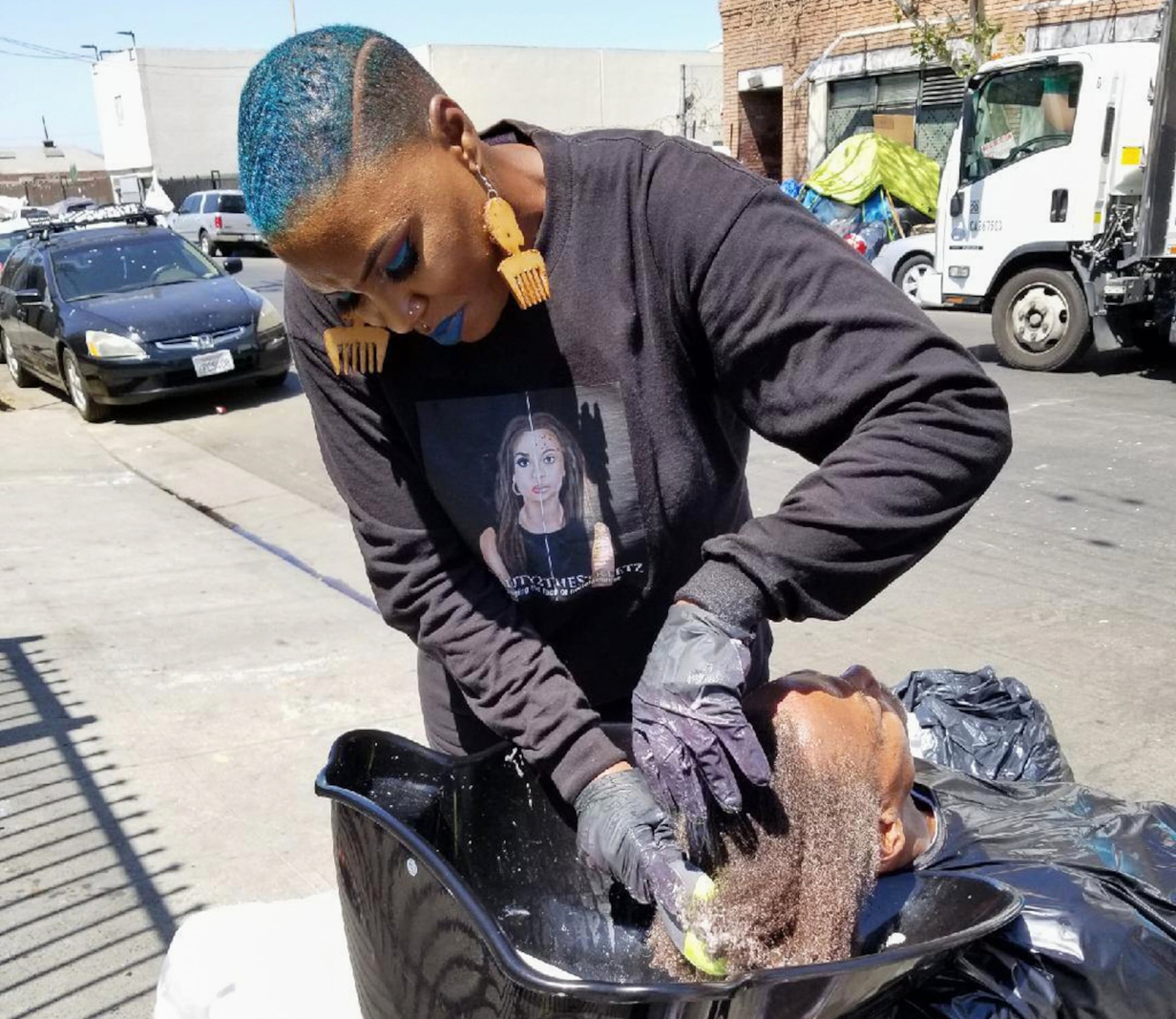 Esta foto proporcionada por Melissa Acedera muestra a Shirley Raines lavándole el cabello a una persona en Skid Row, en Los Ángeles, en 2018.