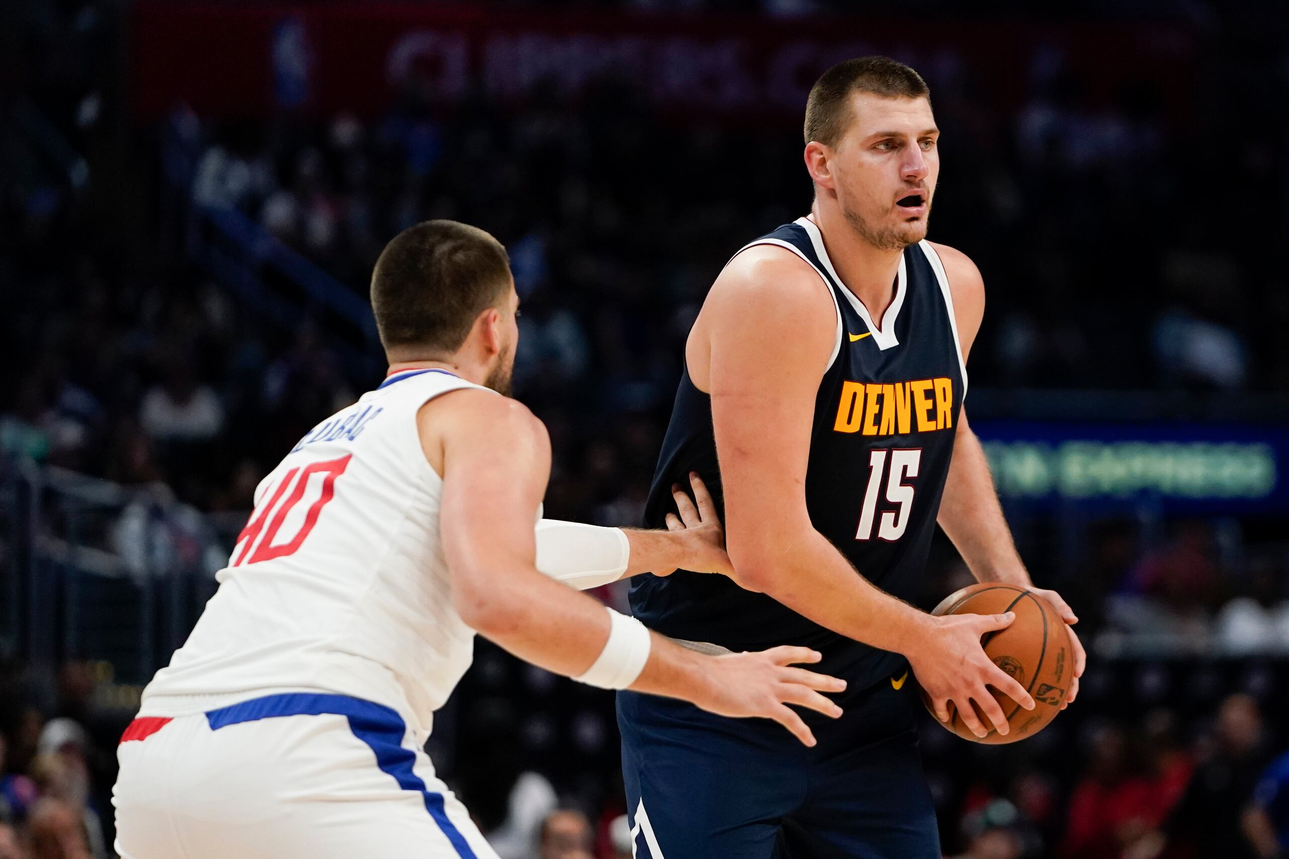 El pívot de los Nuggets de Denver Nikola Jokic busca para pasar el balón durante el encuentro de pretemporada frente a Ivica Zubac de los Clippers de Los Ángeles.