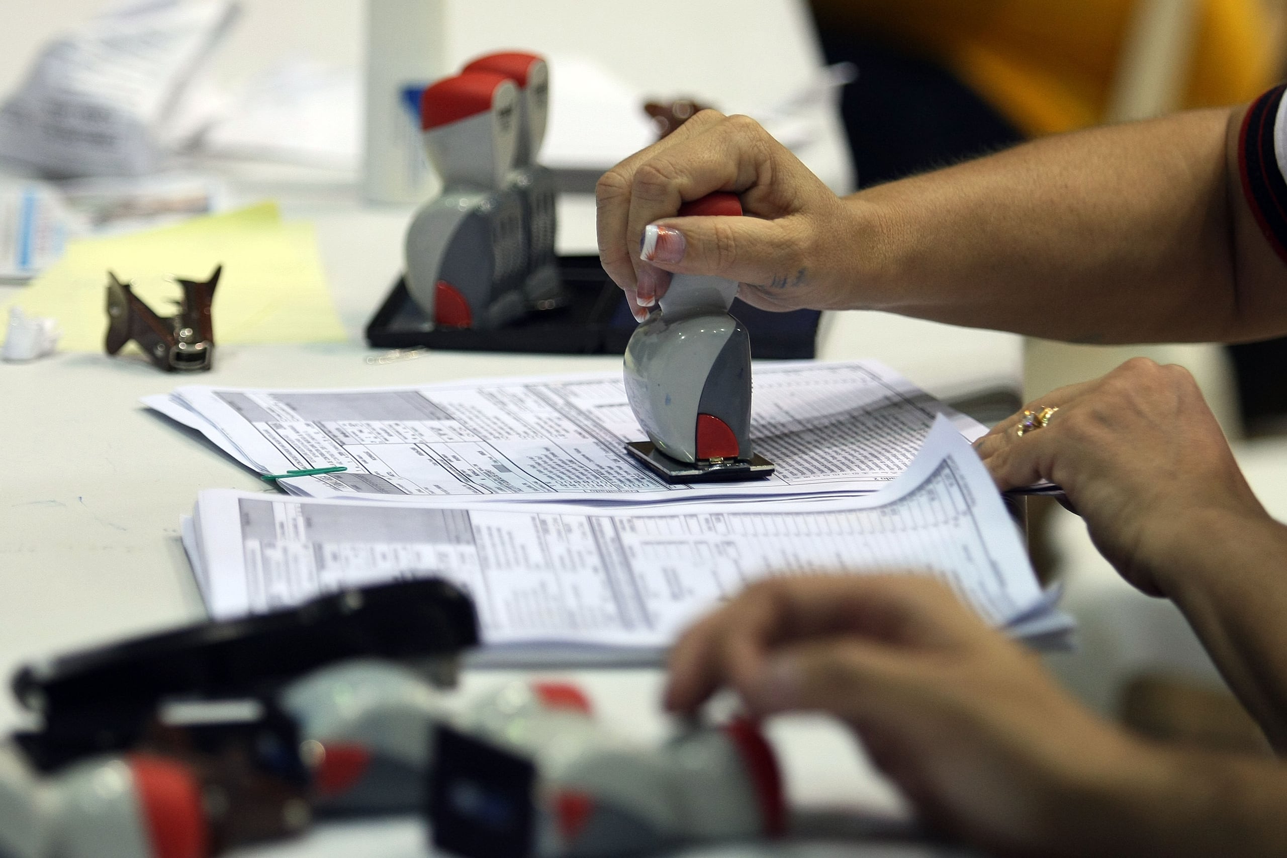 Empleados de Hacienda empleados ponchan unas planillas. (Archivo / GFR Media)