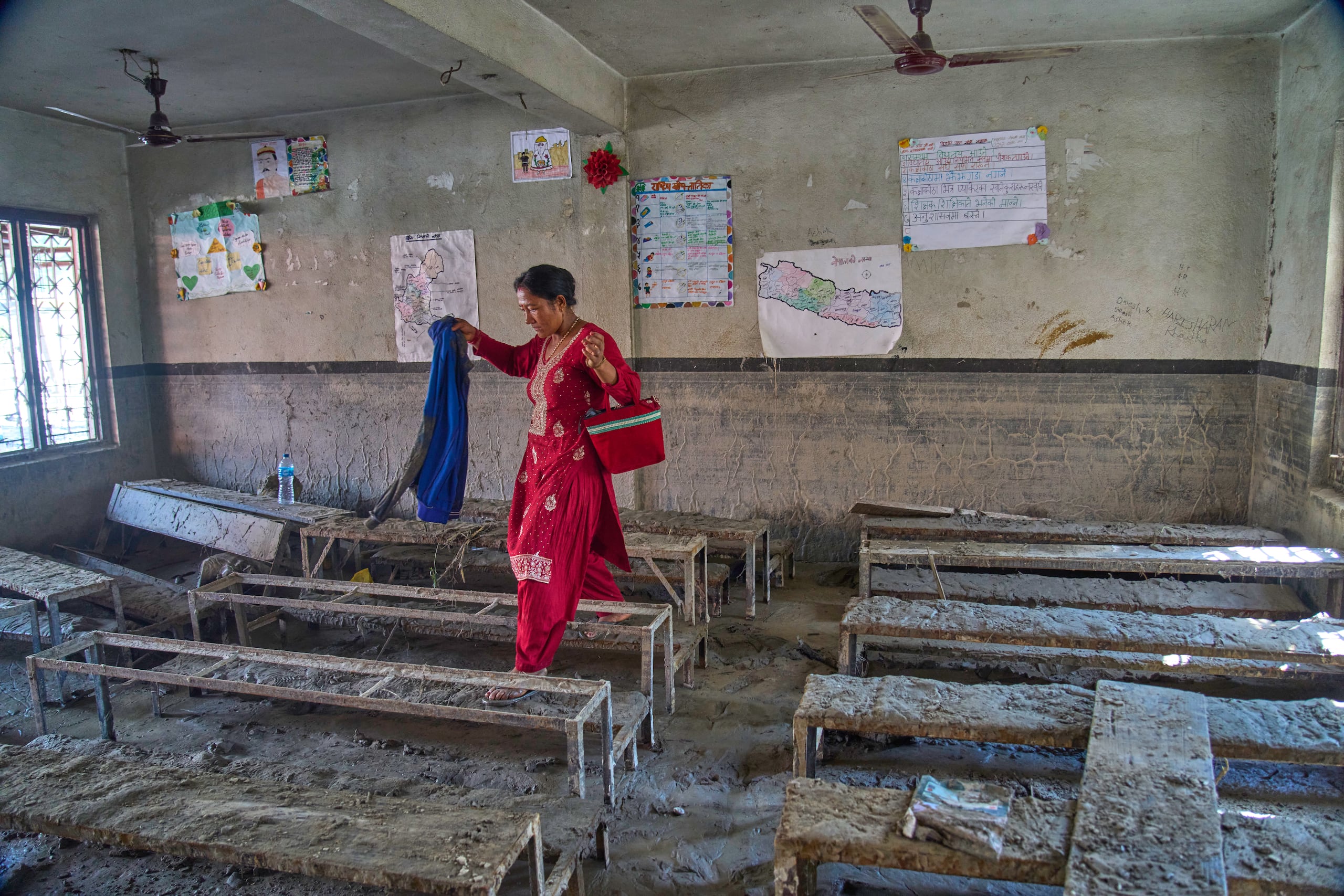 Una madre inspecciona un salón de clases afectado por la inundación en Nepal.