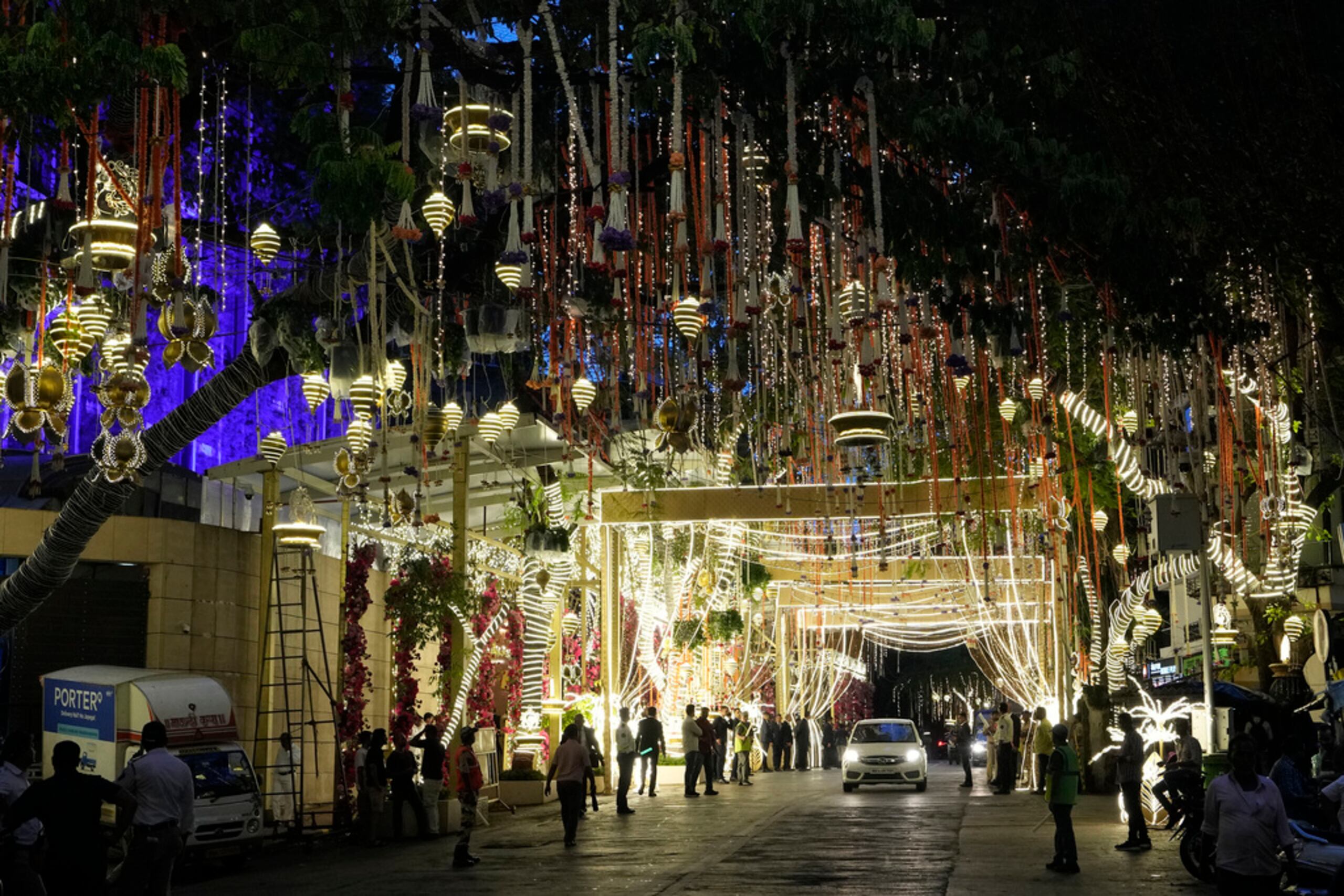 La gente pasa por la mansión Antilia, casa del multimillonario Mukesh Ambani, mientras está iluminada antes de la boda de su hijo Anant Ambani y Radhika Merchant en Mumbai, India, el 10 de julio de 2024.
