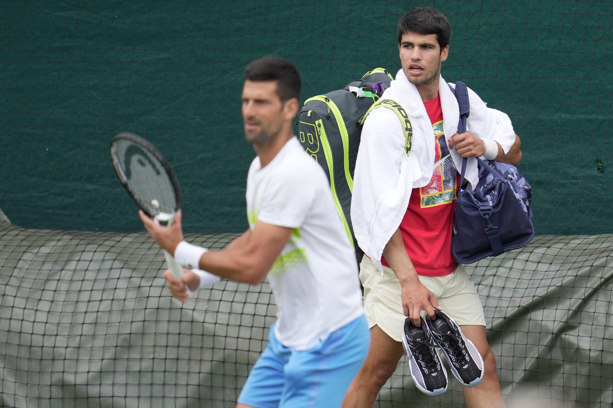 Novak Djokovic y Carlos Alcaraz durante un entrenamiento previo al torneo de Wimbledon, el domingo 2 de julio de 2023. (AP Foto/Kin Cheung)