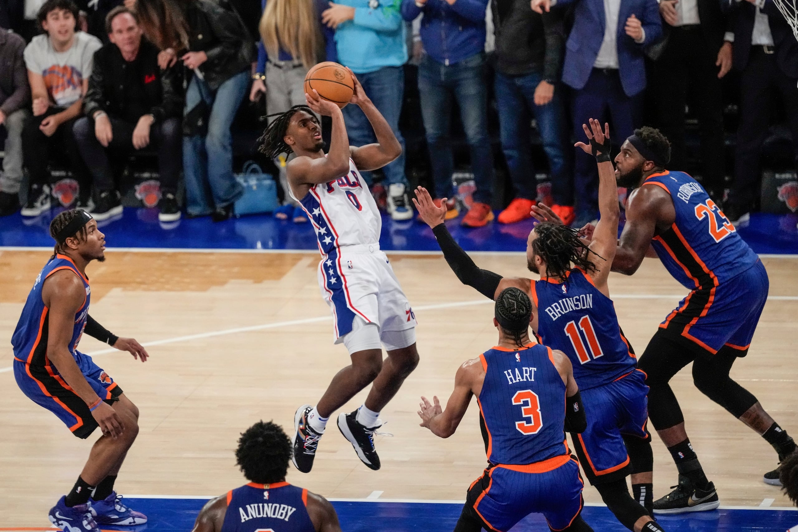 Tyrese Maxey, de los 76ers de Filadelfia, lanza el balón mientras lo defienden Jalen Brunson, Mitchell Robinson y Josh Hart, de los Knicks de Nueva York, en el quinto juego de la serie de primera ronda.