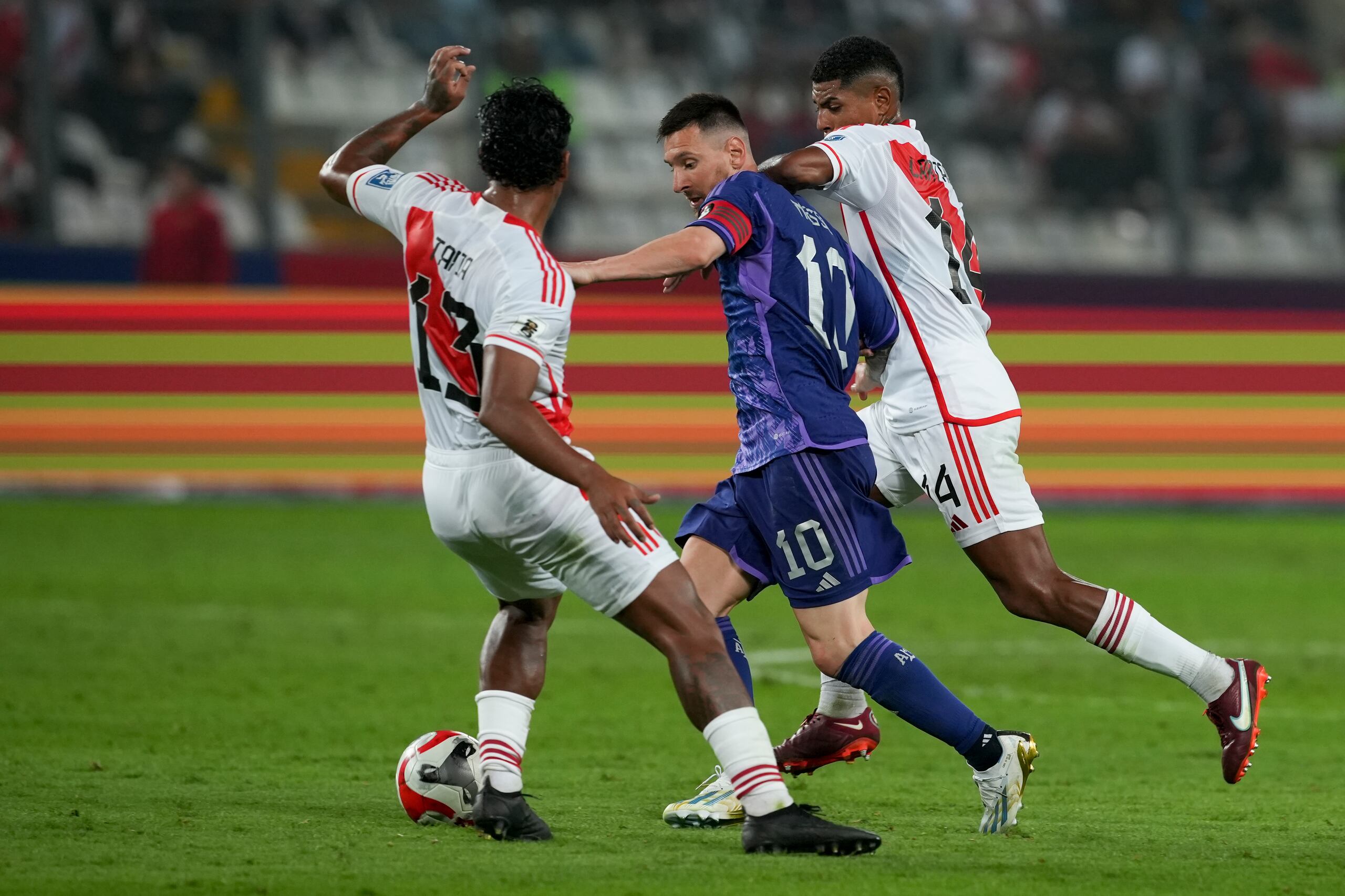 Lionel Messi, de la selección de Argentina, avanza entre Renato Tapia (izquierda) y Wilder Cartagena, de Perú, en un encuentro de la eliminatoria mundialista, el martes 17 de octubre de 2023, en Lima.