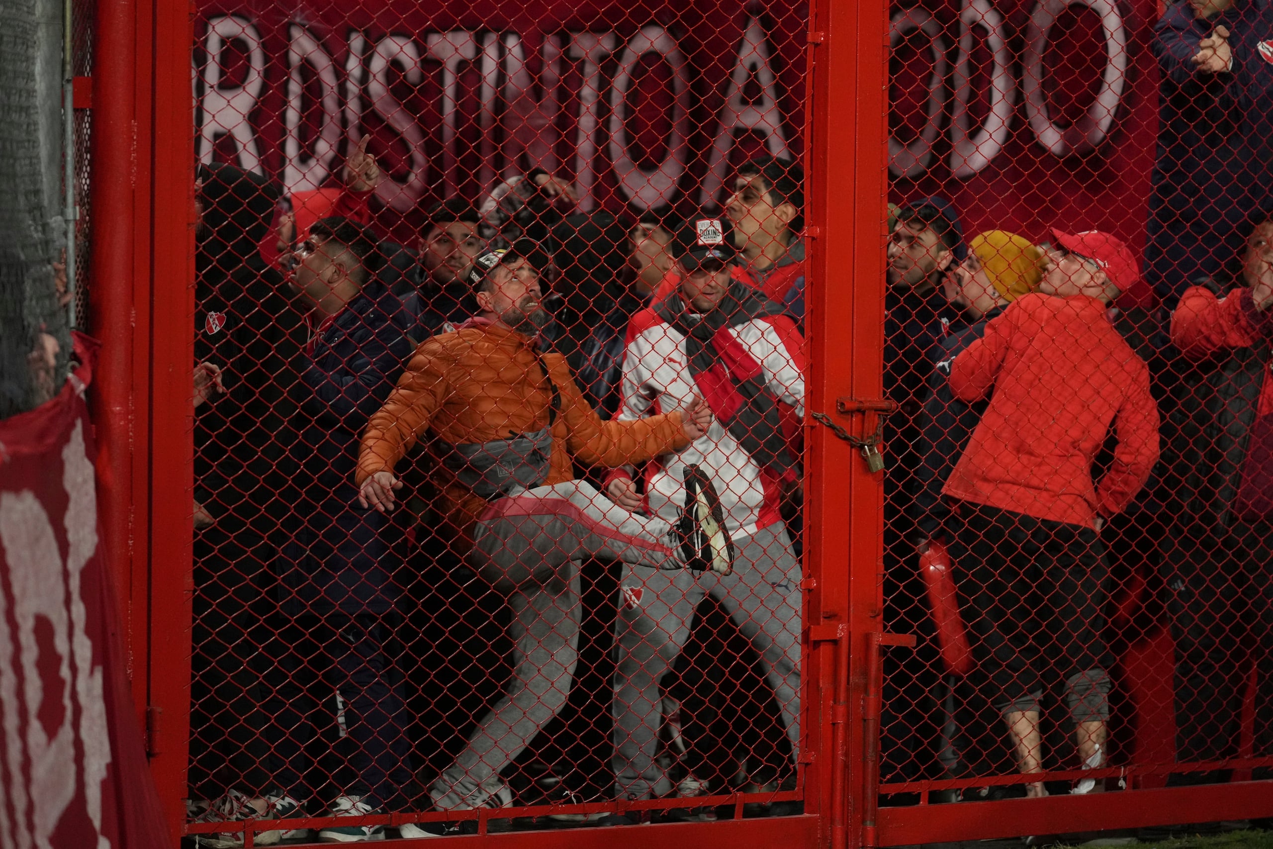 Hinchas de Independiente de Argentina tratan de abrir una reja por la fuerza durante un partido de la Copa Sudamericana ante Universidad de Chile, el miércoles 20 de agosto de 2025 en Avellaneda (AP Foto/Gustavo Garello)