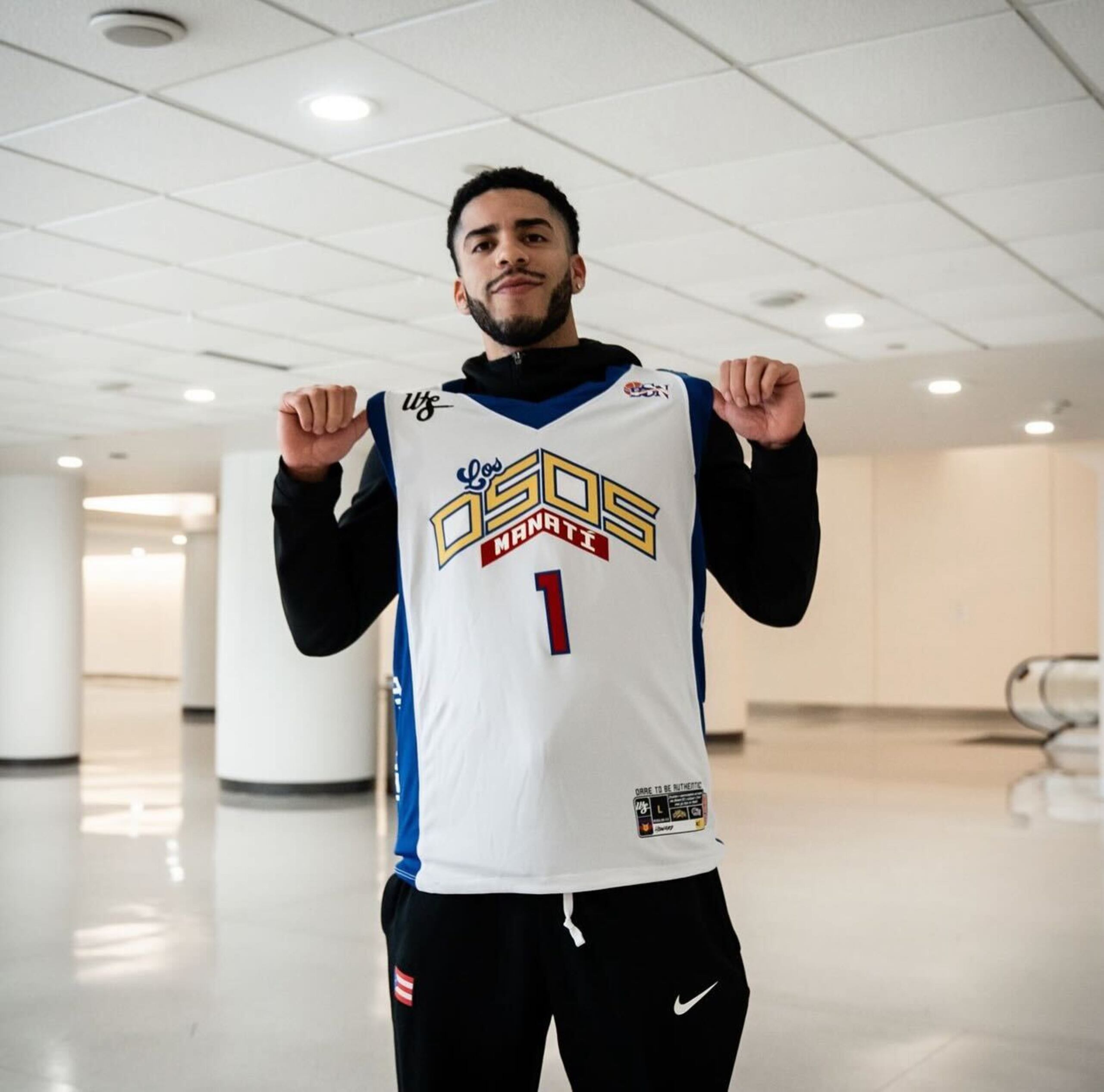 Jordan Howard mostrando el uniforme de los Osos de Manatí en su llegada al Aeropuerto Internacional Luis Muñoz Marín.