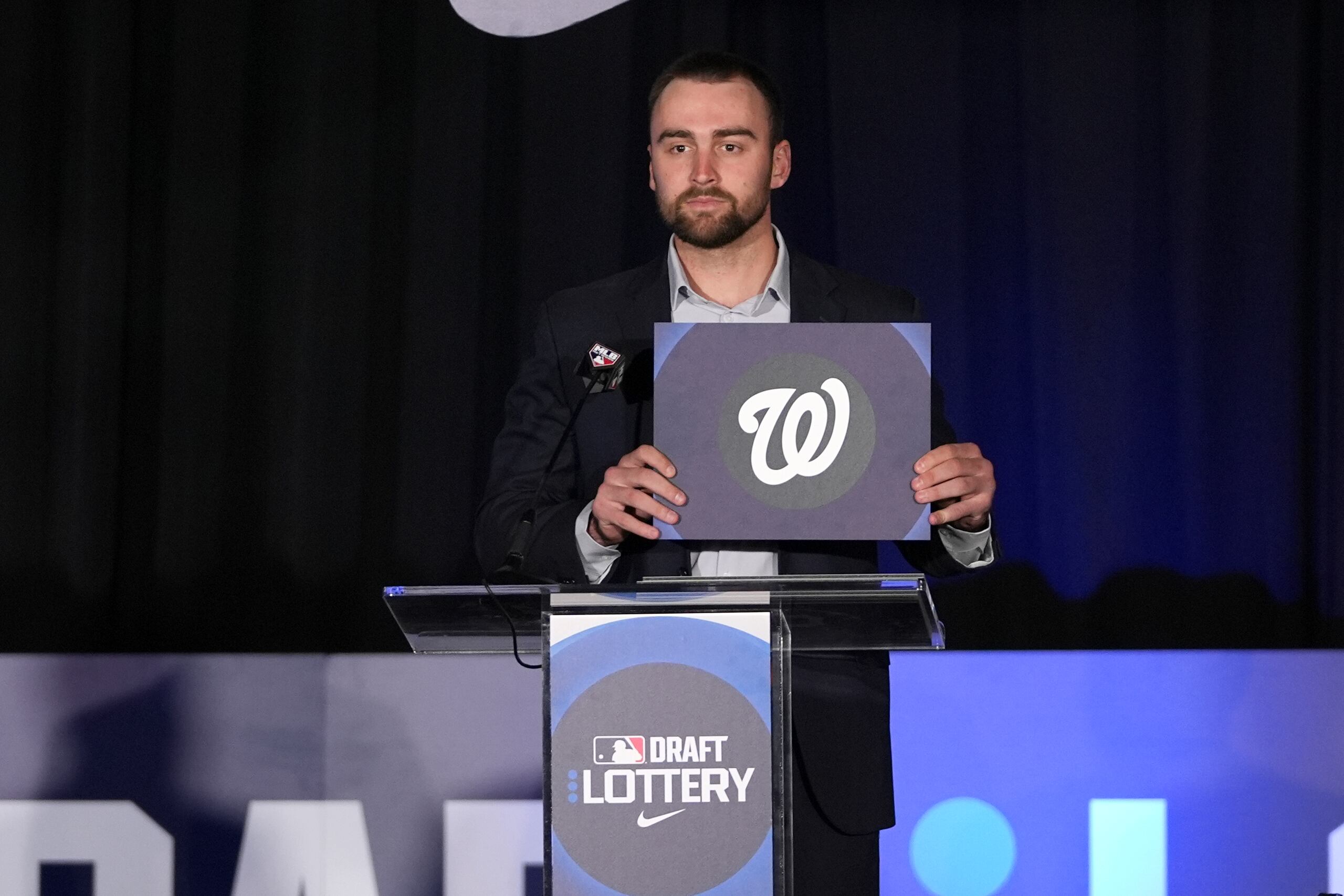 El jardinero de los Orioles de Baltimore, Colton Cowser, sostiene el logotipo de los Nacionales de Washington después de que la organización ganara la selección número uno general en la lotería del draft en las reuniones invernales de las Grandes Ligas en Dallas, el martes 10 de diciembre de 2024.