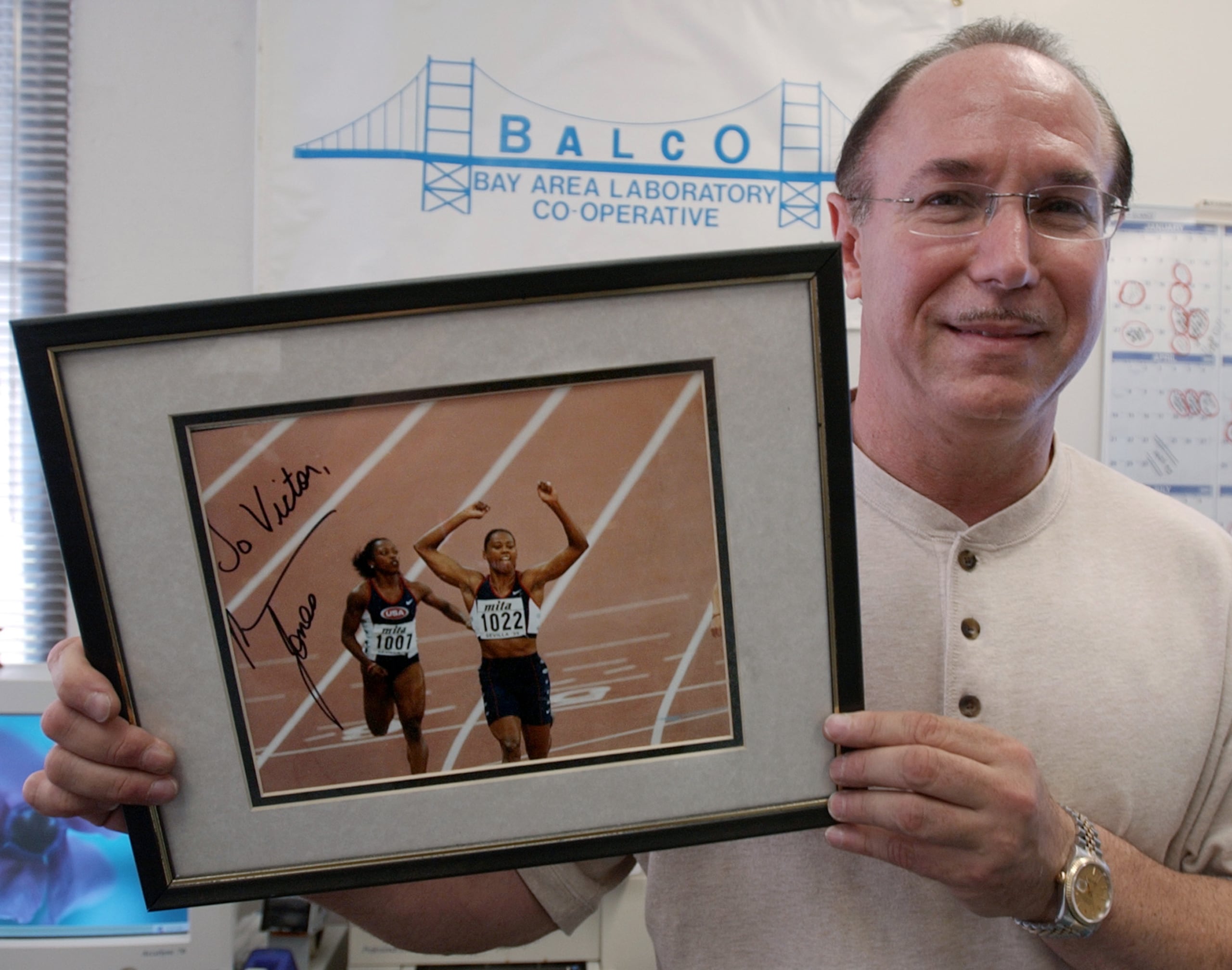 Victor Conte, fundador del labotatorio BALCO, sostiene una fotografía autografiada dedicada a él de la estrella de atletismo Marion Jones en su oficina en Burlingame, California, el 31 de octubre de 2003. (AP Foto/Paul Sakuma, Archivo)