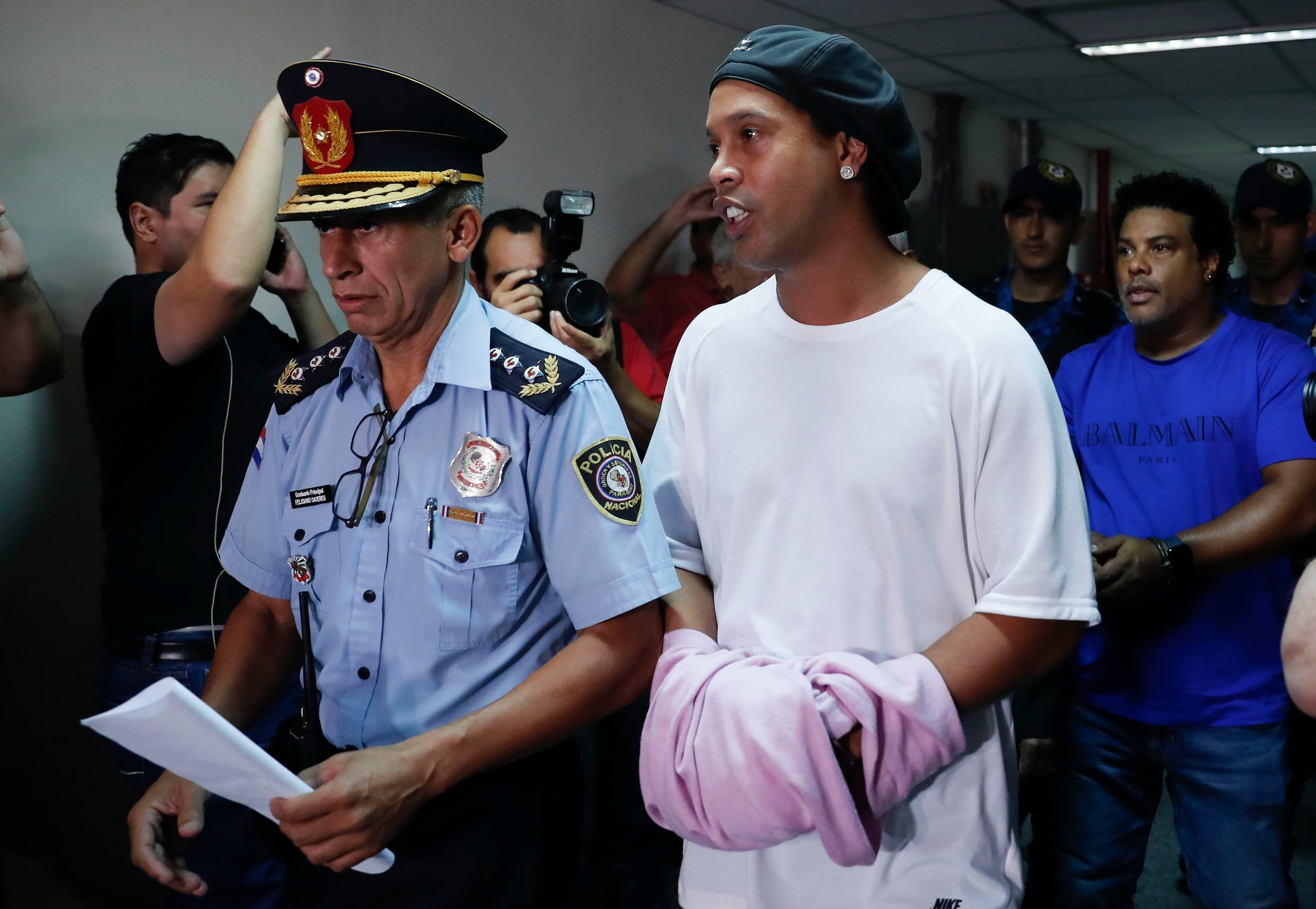 El exastro brasileño de fútbol Ronaldinho camina esposado a una audiencia judicial en Asunción, Paraguay, el sábado, 27 de marzo del 2020.
