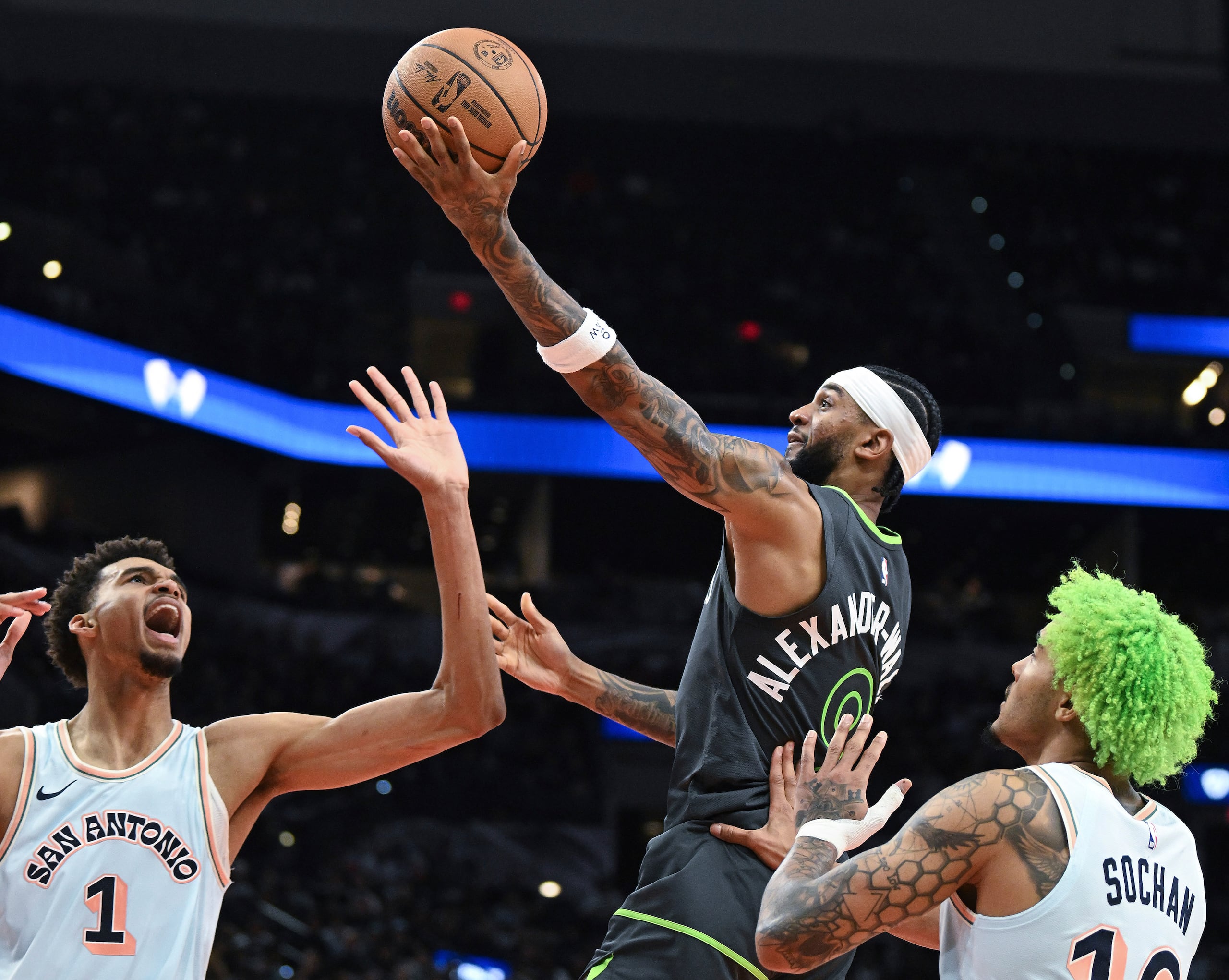 Nickeil Alexander-Walker, centro, de los Timberwolves de Minnesota, prepara una bandeja mientas Victor Wembanyama (1) y Jeremy Sochan, derecha, de los Spurs de San Antonio, defienden durante la segunda mitad del juego de baloncesto de la NBA, el domingo 15 de diciembre de 2024, en San Antonio. (AP Foto/Billy Calzada)