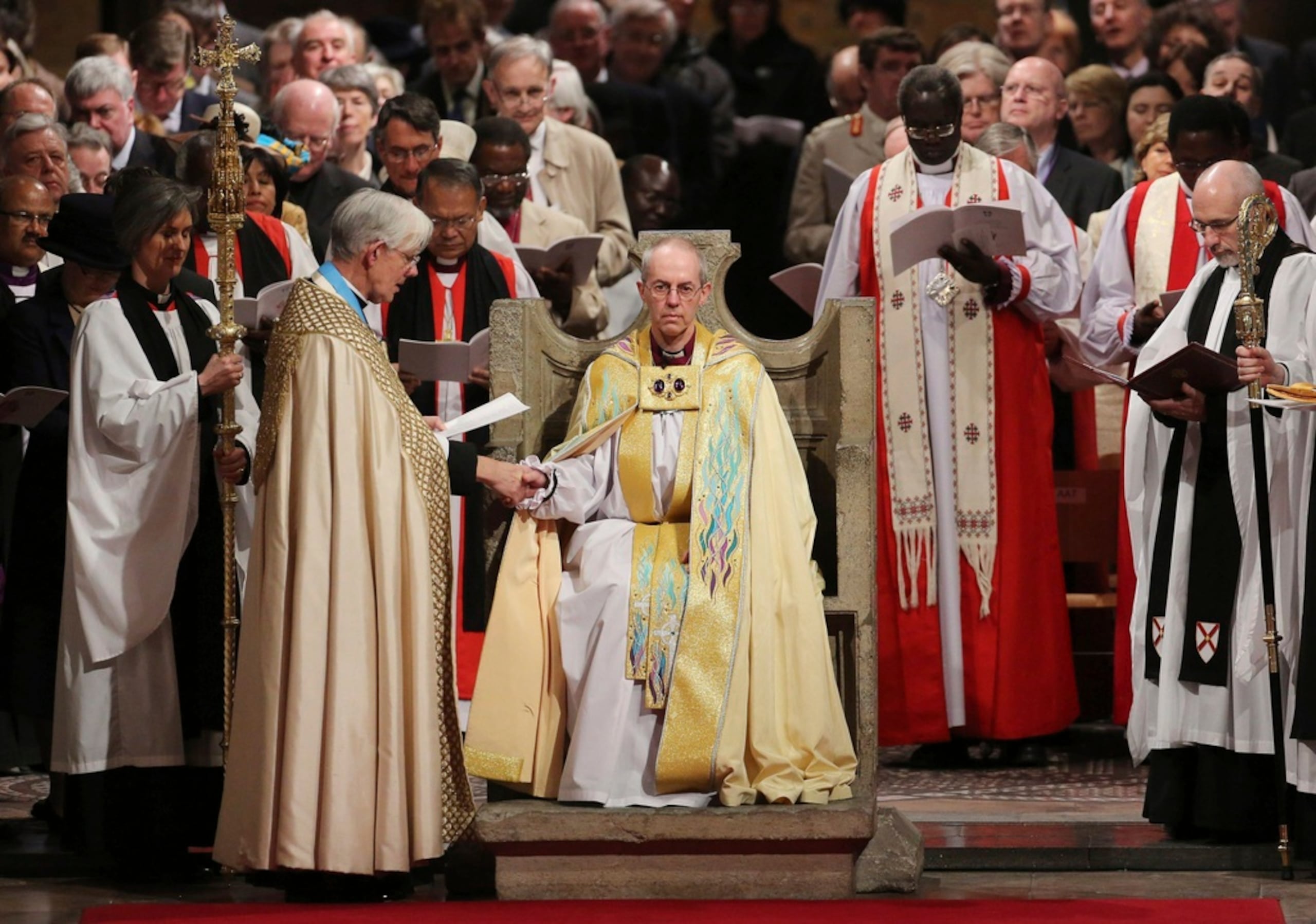 Justin Welby se sienta en la Silla de San Agustín mientras el decano de Canterbury, Robert Willis, lo toma de la mano durante su servicio de entronización para convertirse en Arzobispo de Canterbury en la Catedral de Canterbury, en Canterbury, Inglaterra, el 21 de marzo de 2013.