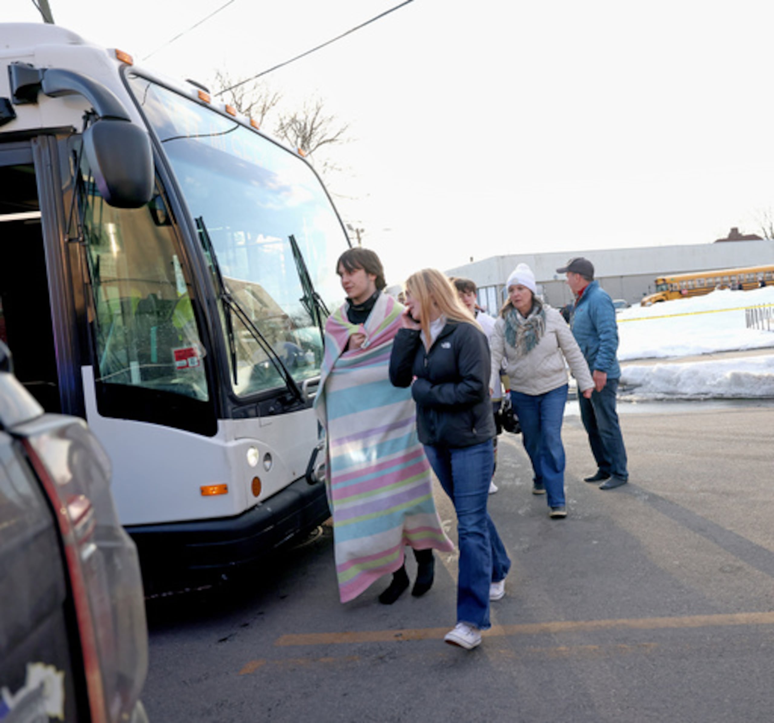 Estudiantes de hockey de secundaria suben a un autobús de transporte público cerca del Lynch Arena en Pawtucket, Rhode Island, después de un tiroteo en la pista de hielo, el lunes 16 de febrero de 2026. (AP Photo/Mark Stockwell)