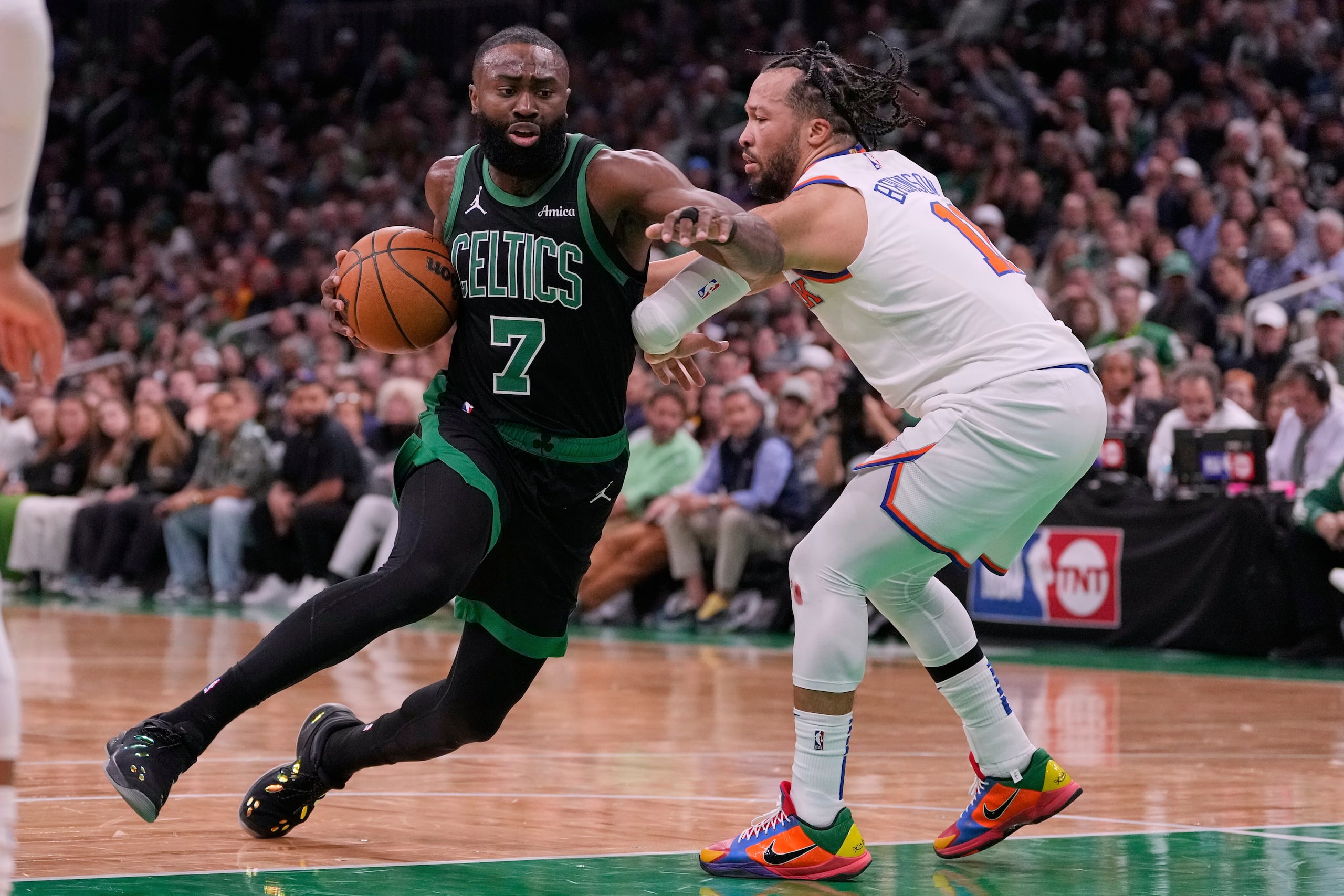 Jaylen Brown (7), de los Celtics de Boston, dribla hacia la canasta frente a Jalen Brunson, derecha, de los Knicks de Nueva York, durante la primera mitad del quinto juego de la serie de segunda ronda de playoffs del baloncesto de la NBA, el miércoles 14 de mayo de 2025, en Boston. (AP Foto/Charles Krupa)
