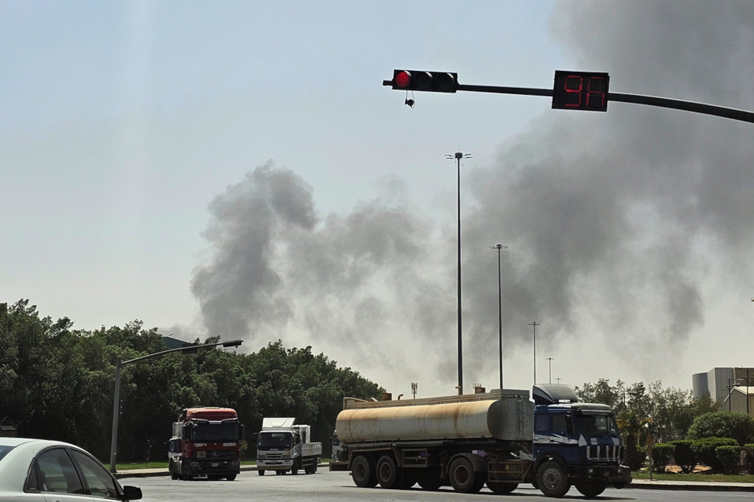 Varios vehículos transitan por una carretera mientras emerge una densa columna de humo negro de un incendio en una instalación petrolera, en una zona industrial en el sur de Riad, Arabia Saudí, el 3 de octubre de 2026.