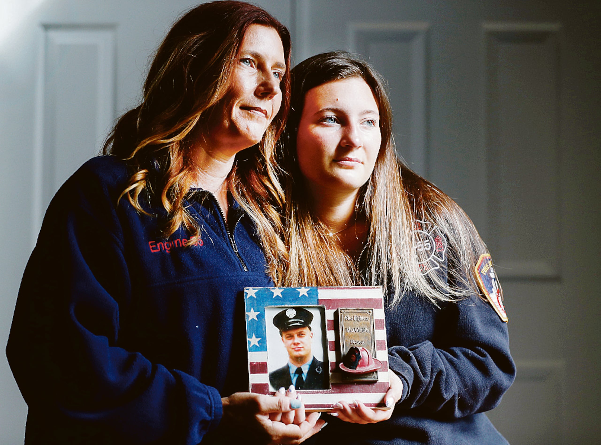 Pamela y Capri Yarosz cargan una foto del bombero Christopher Michael Mozzillo.