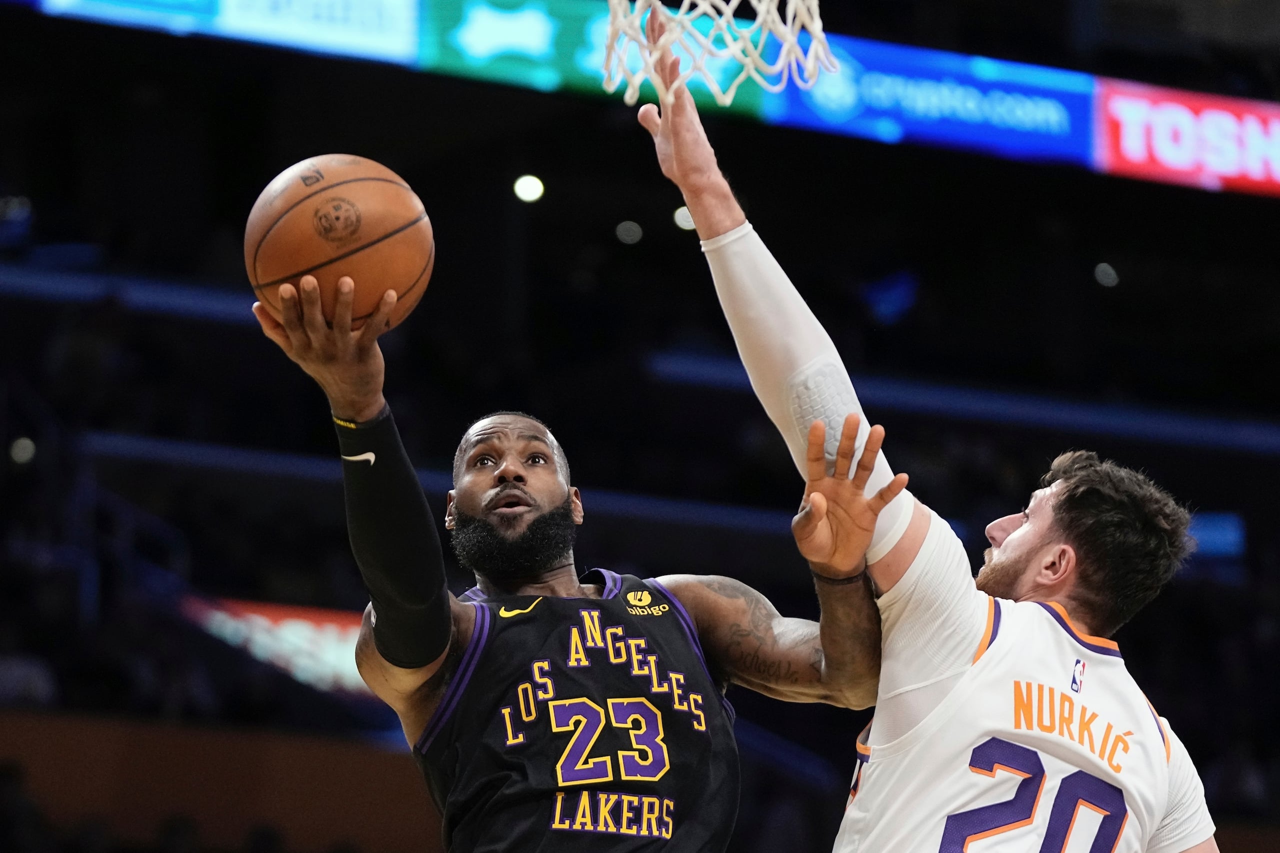 El alero de los Lakers de Los Ángeles LeBron James lanza el balón a la canasta mientras lo defiende el pívot de los Suns de Phoenix Jusuf Nurkic en el encuentro de la Copa de la NBA.