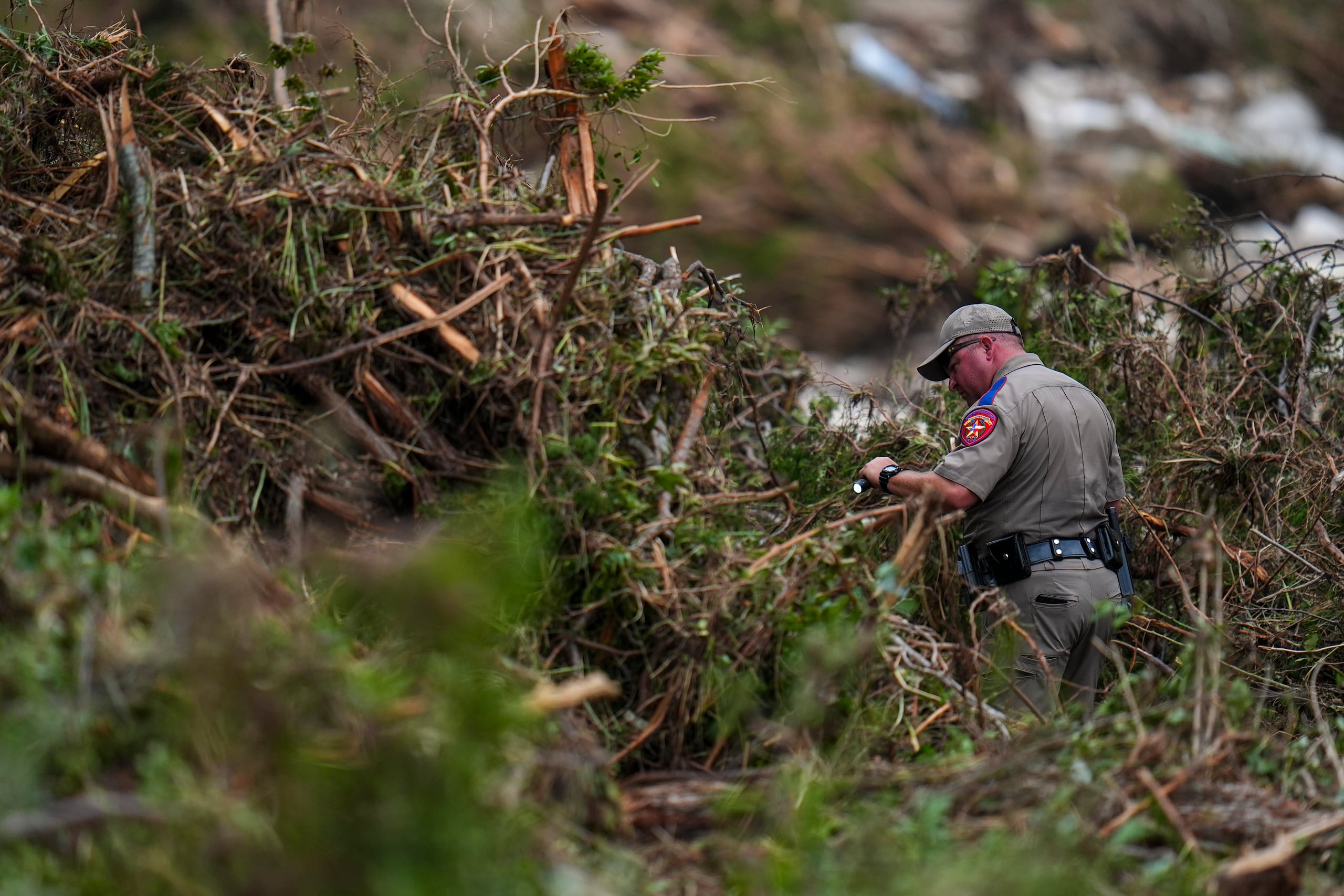 Un funcionario del Departamento de Salud Pública de Texas busca en las orillas del río Guadalupe cerca de Camp Mystic después de una inundación repentina, el sábado 5 de julio de 2025 en Hunt, Texas. (AP Foto/Julio Cortez)