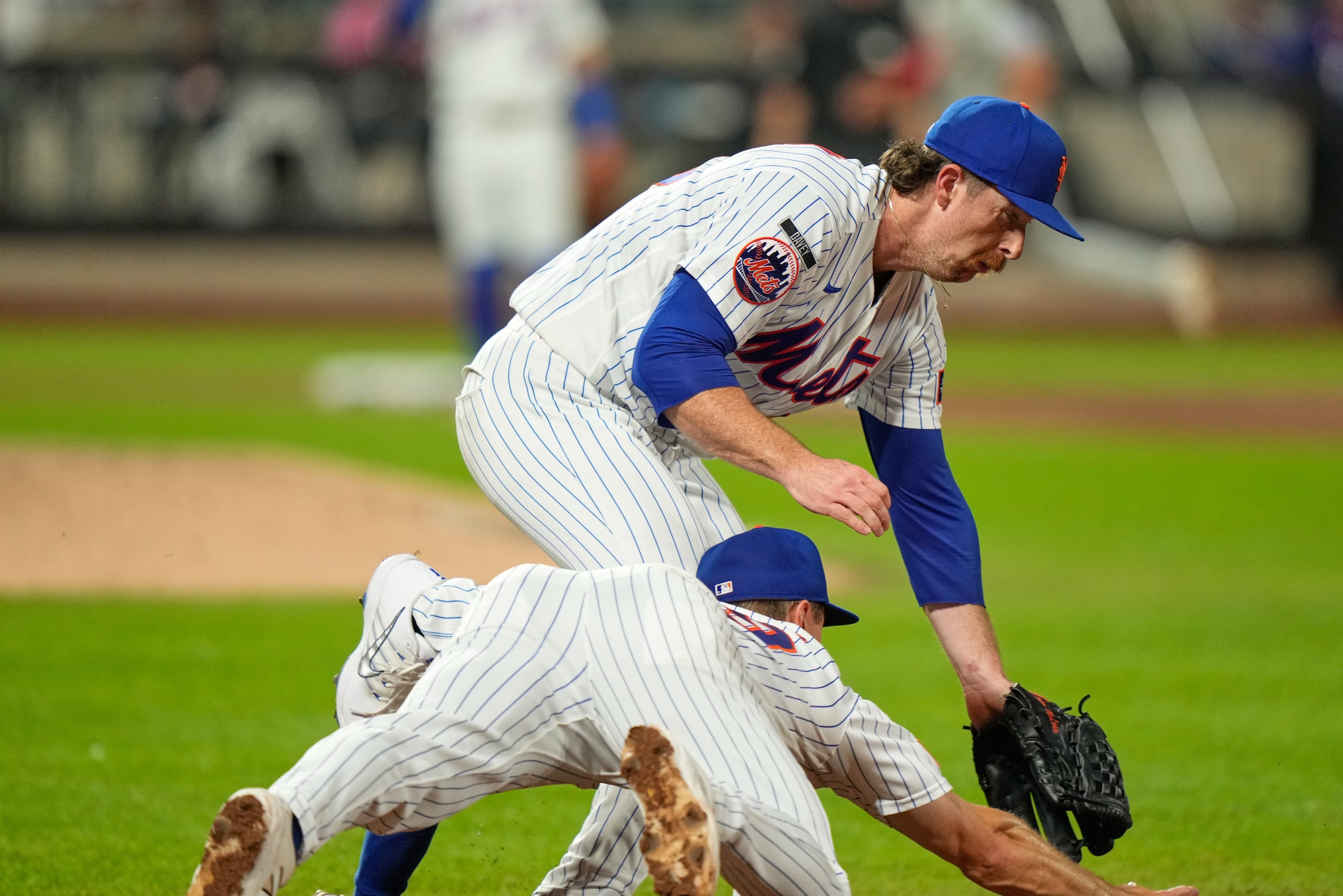 El lanzador de los Mets de Nueva York, Nolan McLean, choca con el inicialista Jared Young mientras ambos persiguen una pelota.
